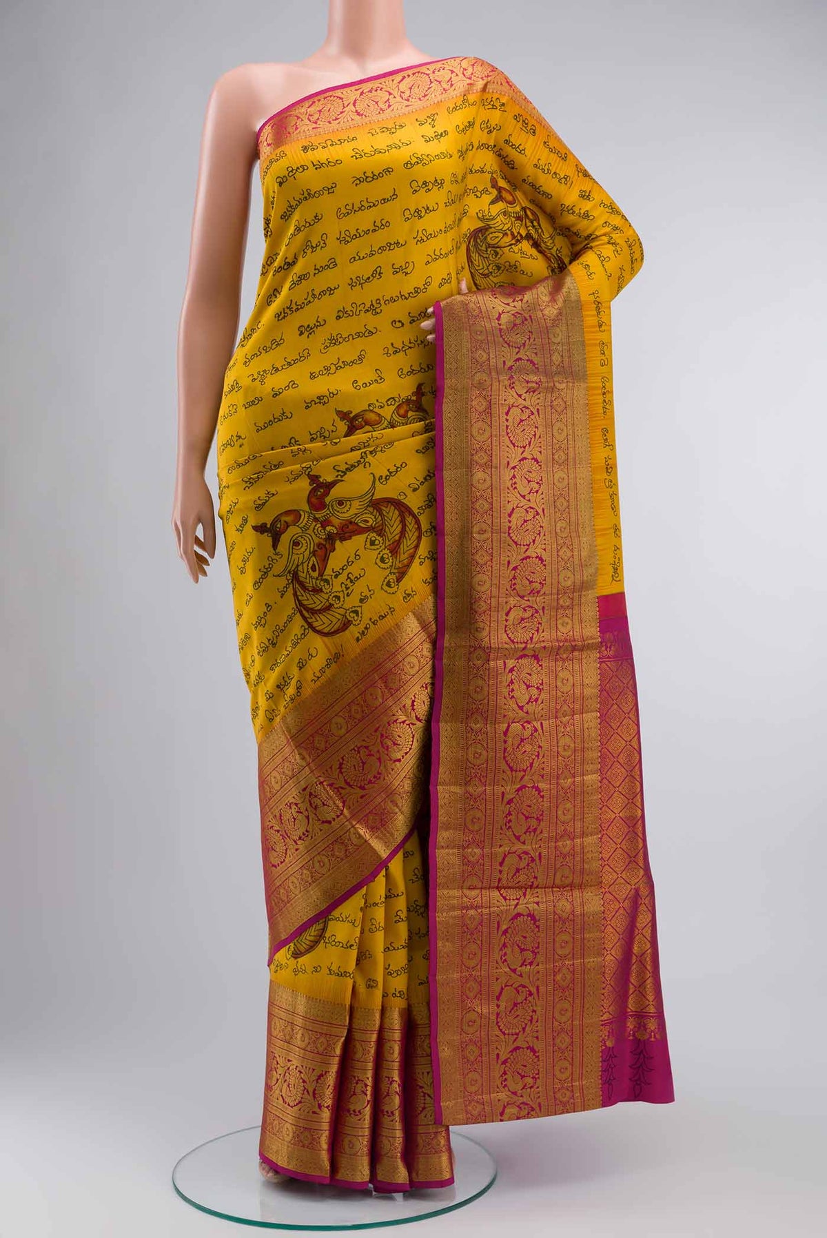 Mustard Kanchipuram Silk Saree with kalamkari Print on the body and Zari Border displayed on a mannequin
