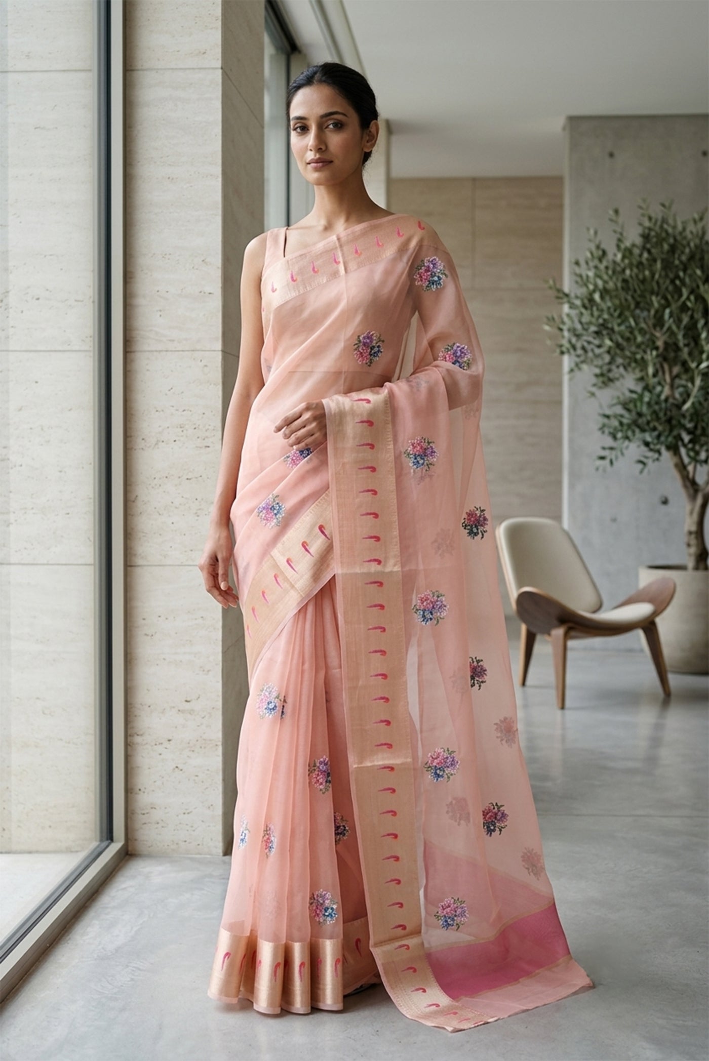 Model wearing a Rose pink Organza Silk Saree with Embroidery on the body and Zari Border.