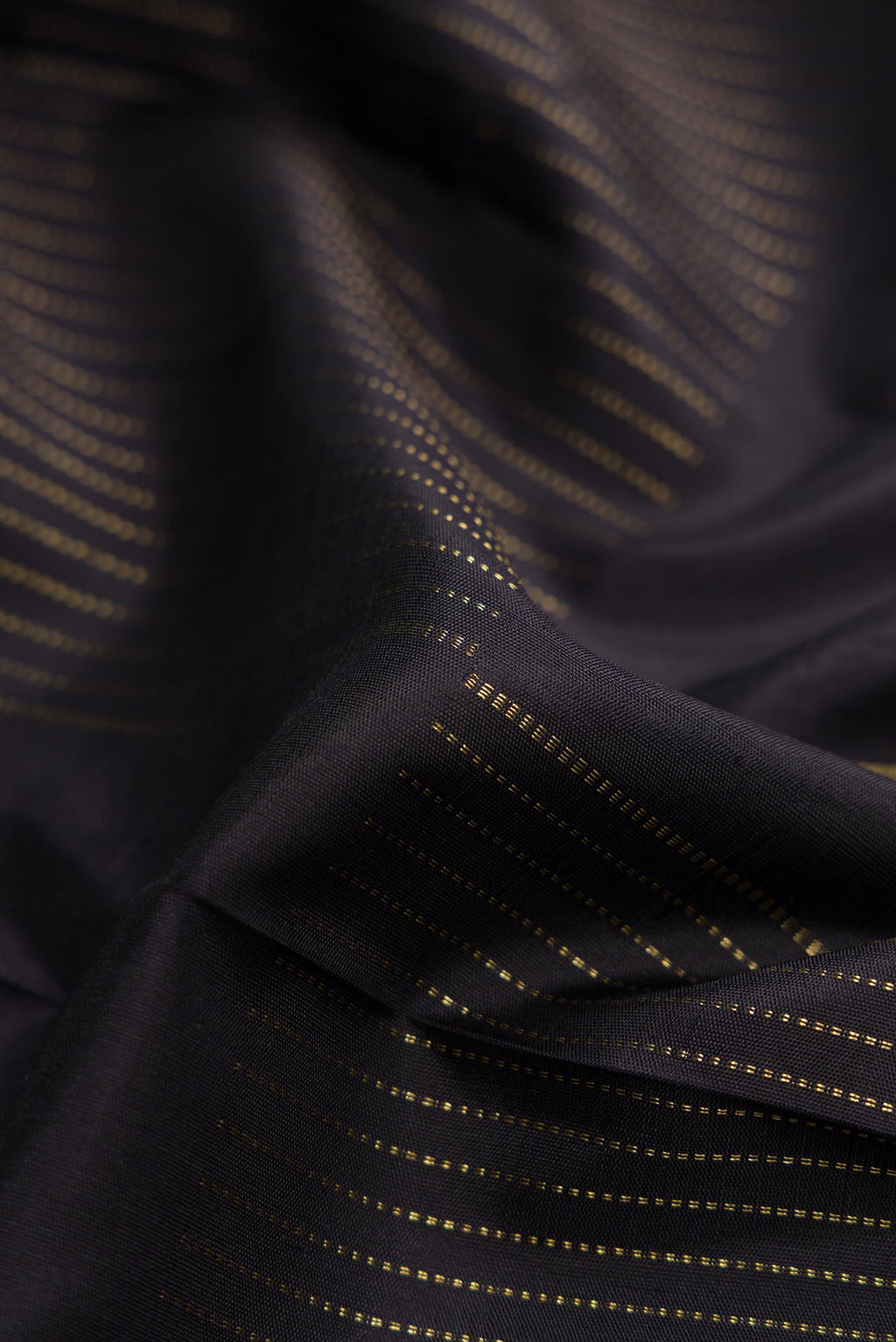 Close up of Pure Silk Pure Zari Coffee Brown Dual Tone Kanchipuram Saree with Zari Butta on the body and Thin Zari Line displaying folds