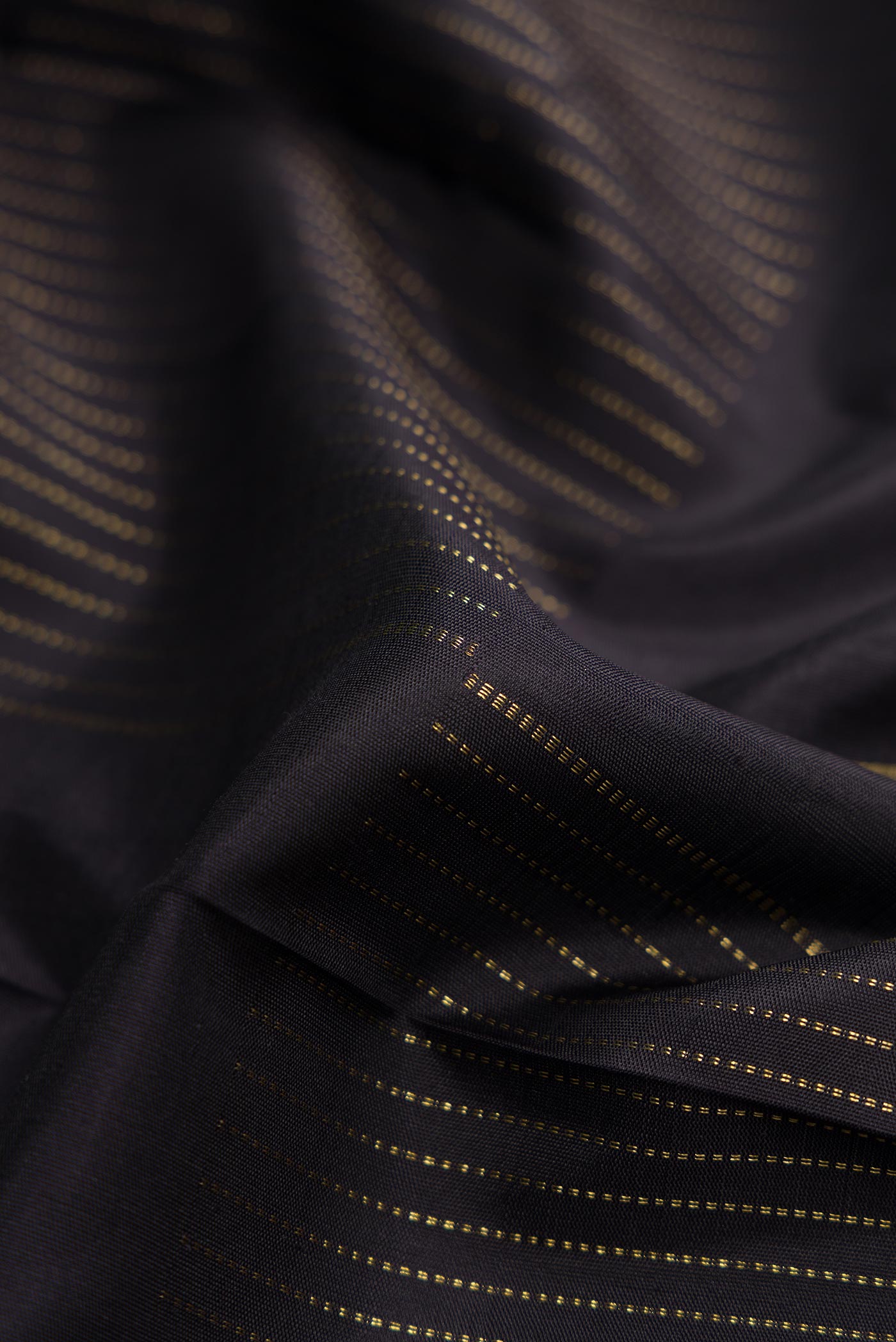 Close up of Pure Silk Pure Zari Coffee Brown Dual Tone Kanchipuram Saree with Zari Butta on the body and Thin Zari Line displaying folds