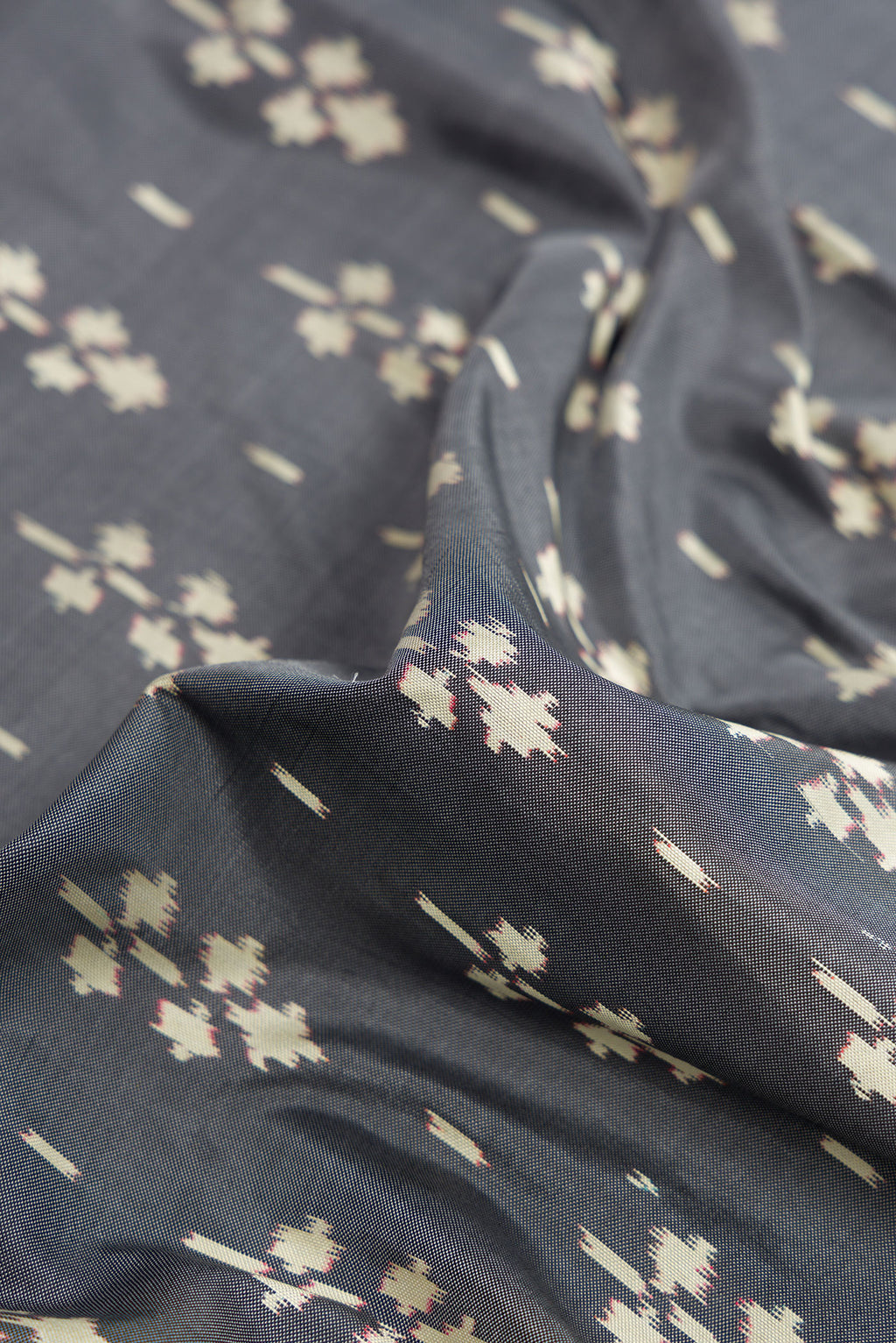 Close up of Grey Dual Tone Double Ikat Saree with Ikat Print on the body and Zari Border.  displaying folds