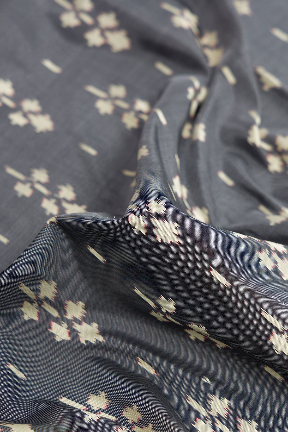 Close up of Grey Dual Tone Double Ikat Saree with Ikat Print on the body and Zari Border.  displaying folds