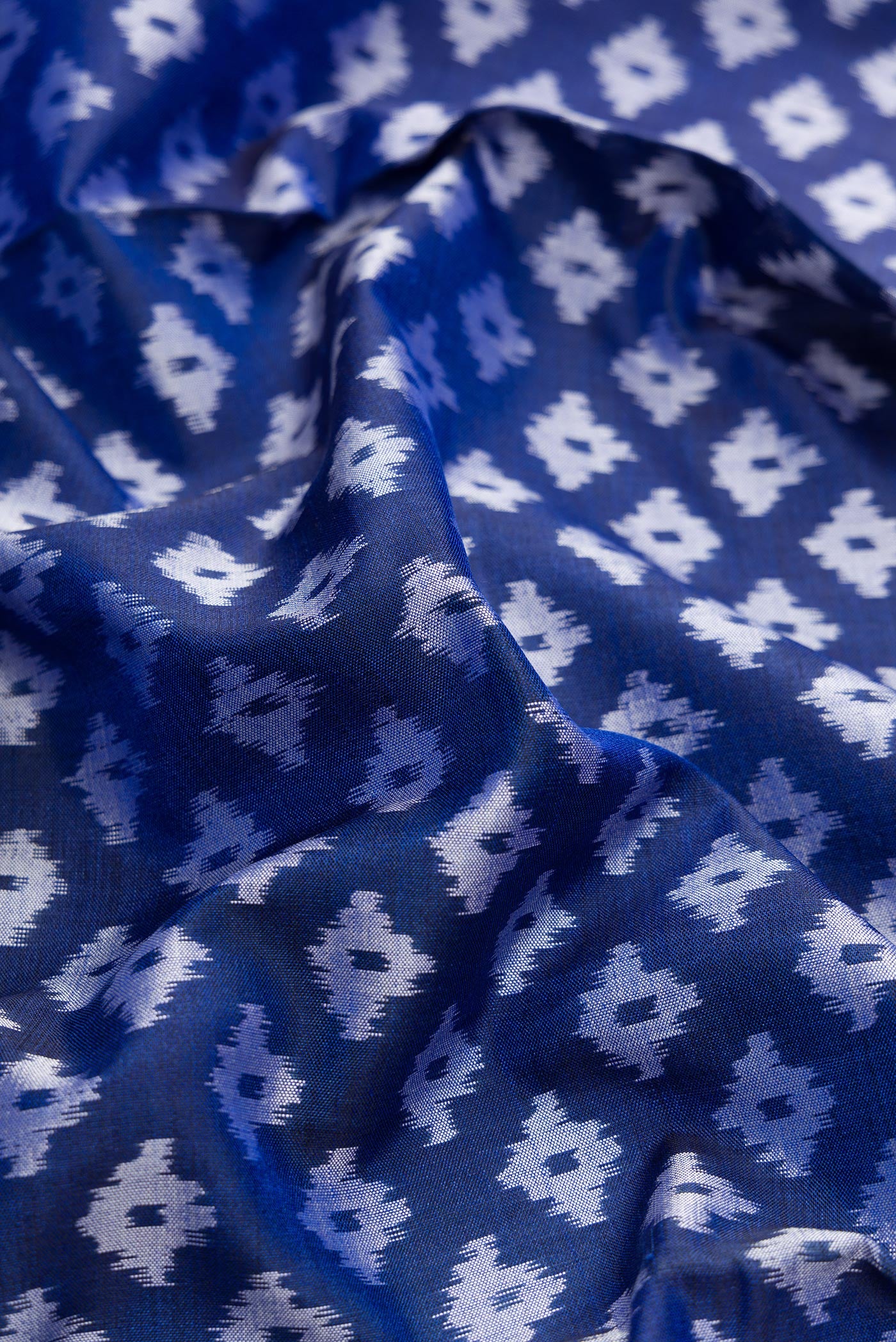 Close up of Royal Blue Dual Tone Double Ikat Saree with Ikat Print on the body and Plain Border.  displaying folds
