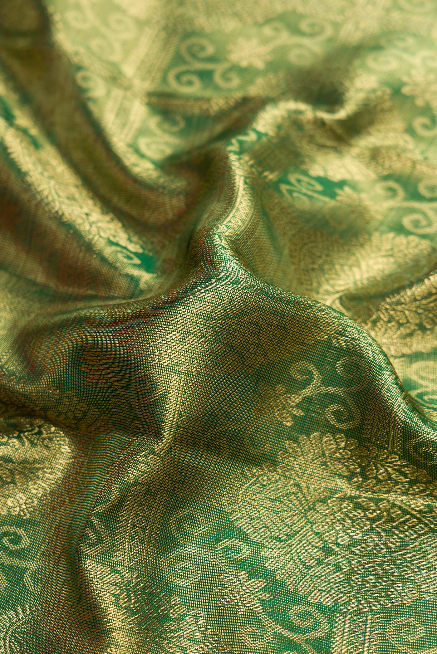 Close up of Green Dual Tone Kanchipuram Silk Saree with Zari Brocade on the body and Zari Border.  displaying folds