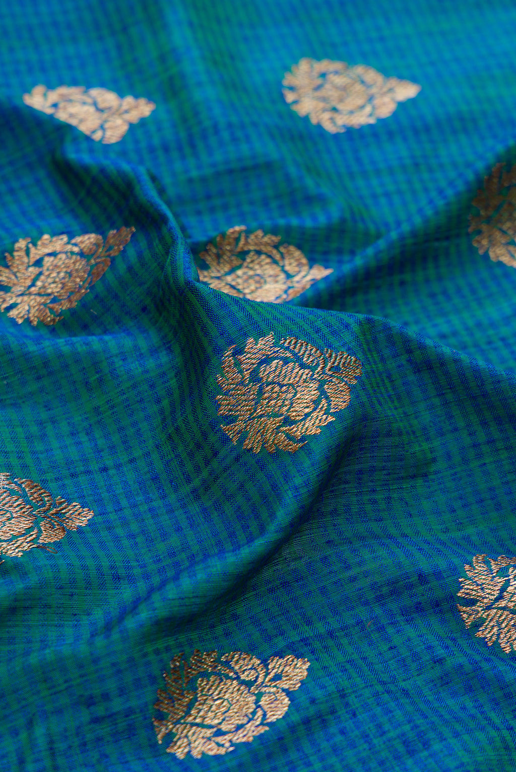 Close up of Peacock Blue Dual Tone Banarasi Silk Saree with Zari Butta on the body and Fancy Border.  displaying folds