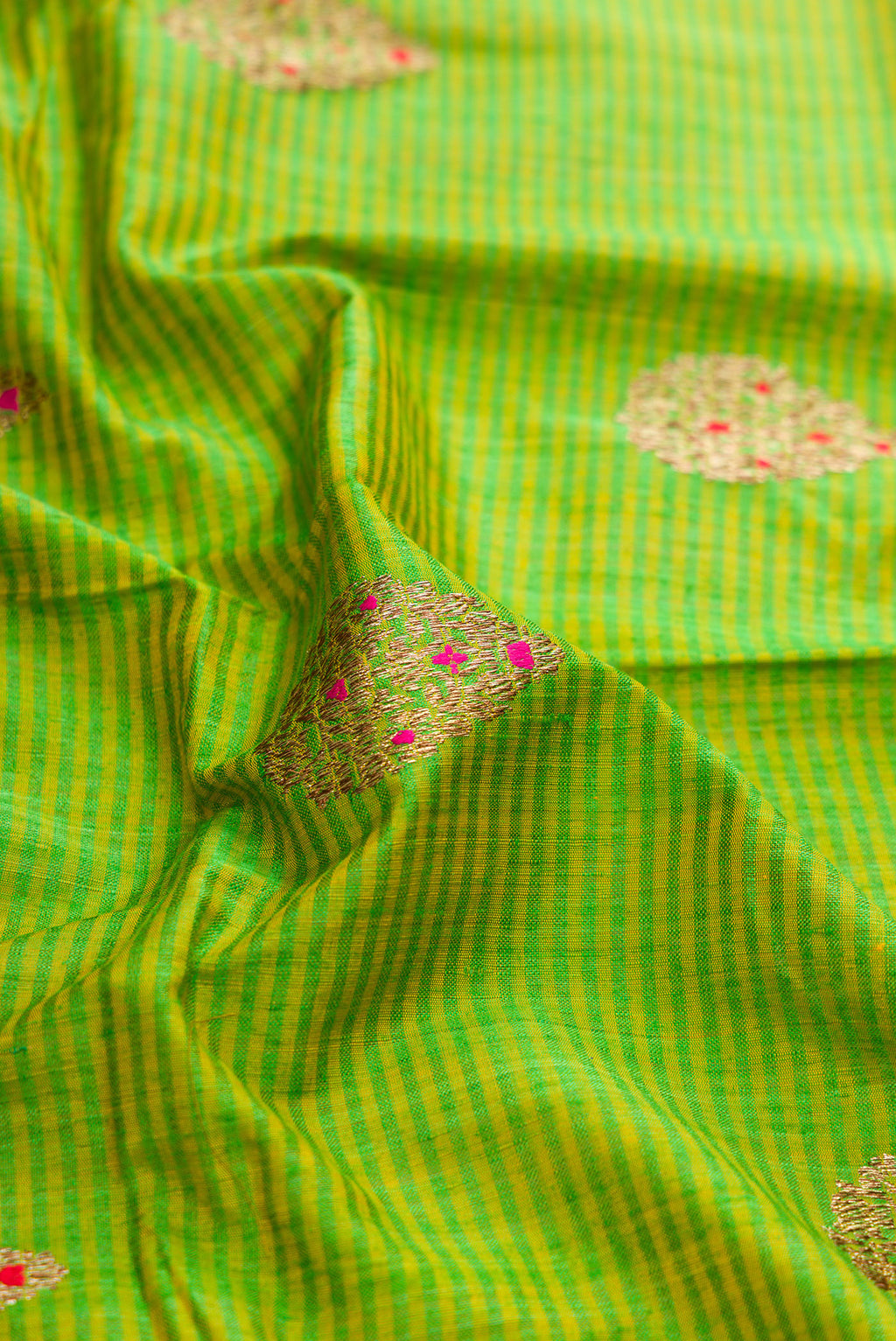 Close up of Parrot Green Dual Tone Banarasi Silk Saree with Zari Butta on the body and Fancy Border.  displaying folds