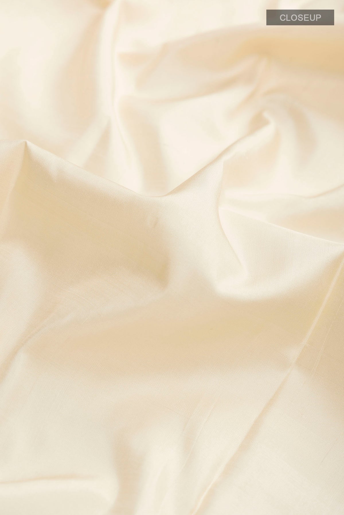 Close up of Cream Kanchipuram Silk Saree with Plain Body and Plain Border displaying folds