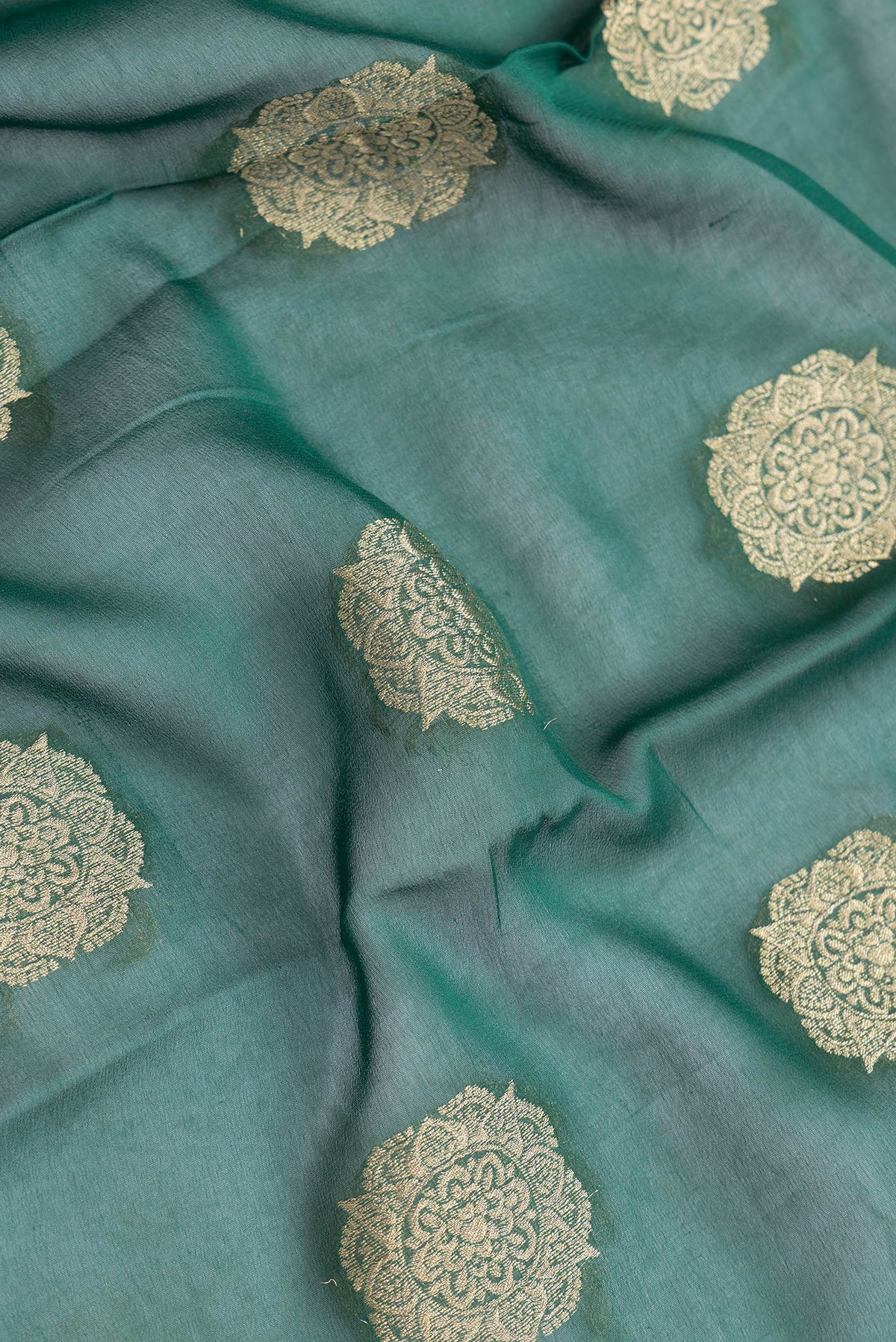 Close up of Bottle Green Dual Tone Mysore Georgette Saree with Zari Butta on the body and Zari Border.  displaying folds