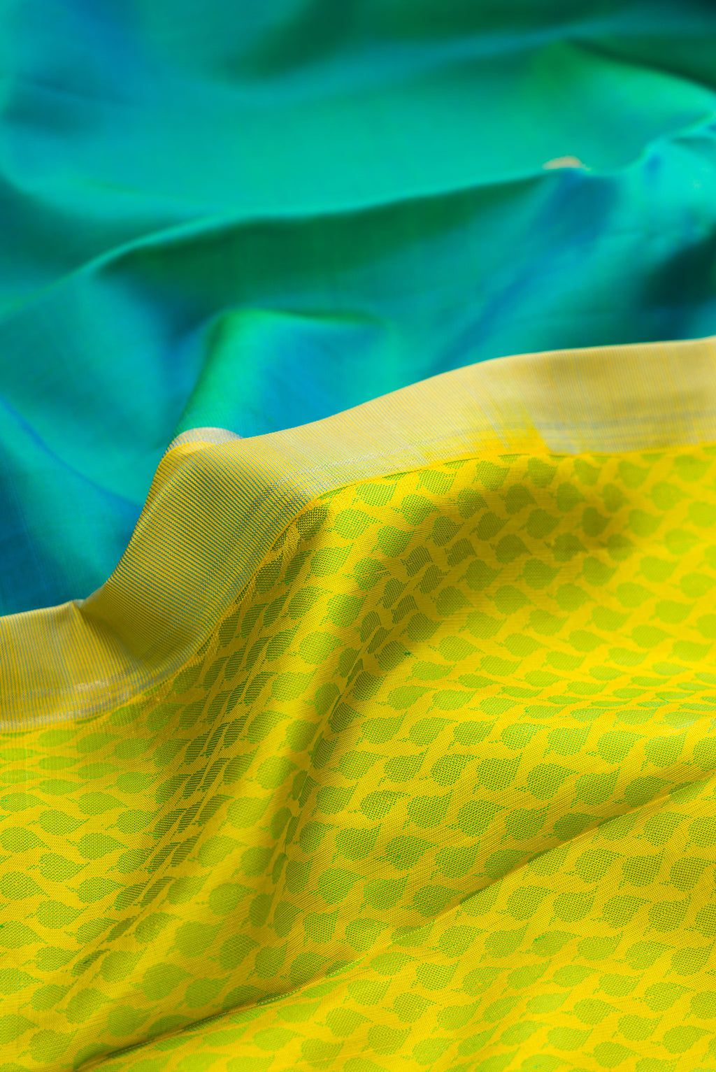 Close up of Yellow Dual Tone Kanjivaram Silk Saree with Half And Half on the body and Without Border.  displaying folds