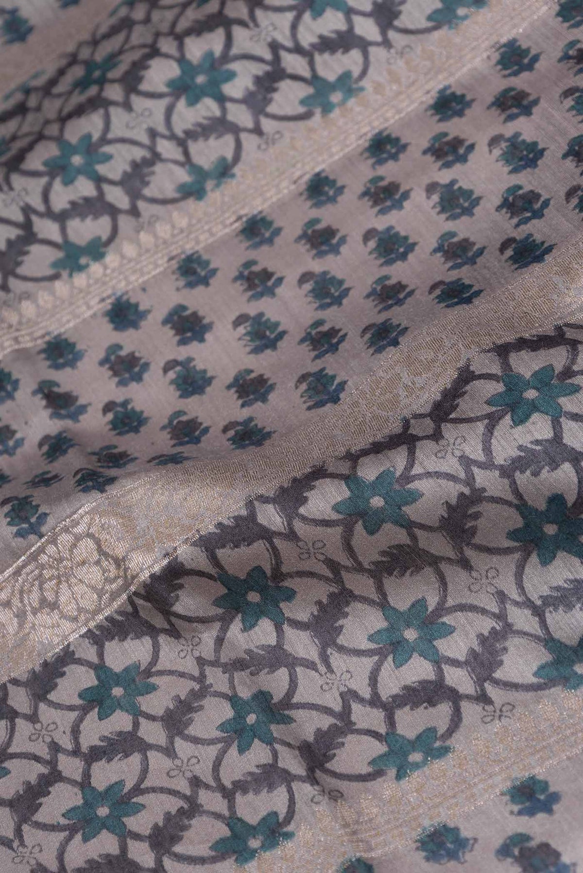 Close up of Grey Dual Tone Tussar Silk Saree with Printed design on the body and Embroidery Border displaying folds
