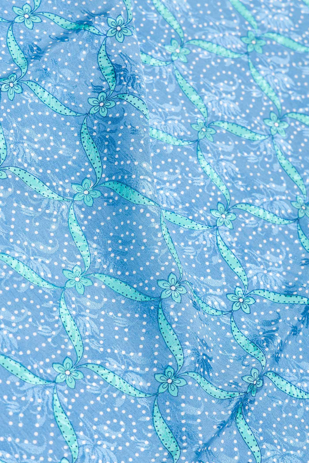 Close up of Sky Blue Dual Tone Mysore Crepe Saree with Printed design on the body and Zari Border.  displaying folds
