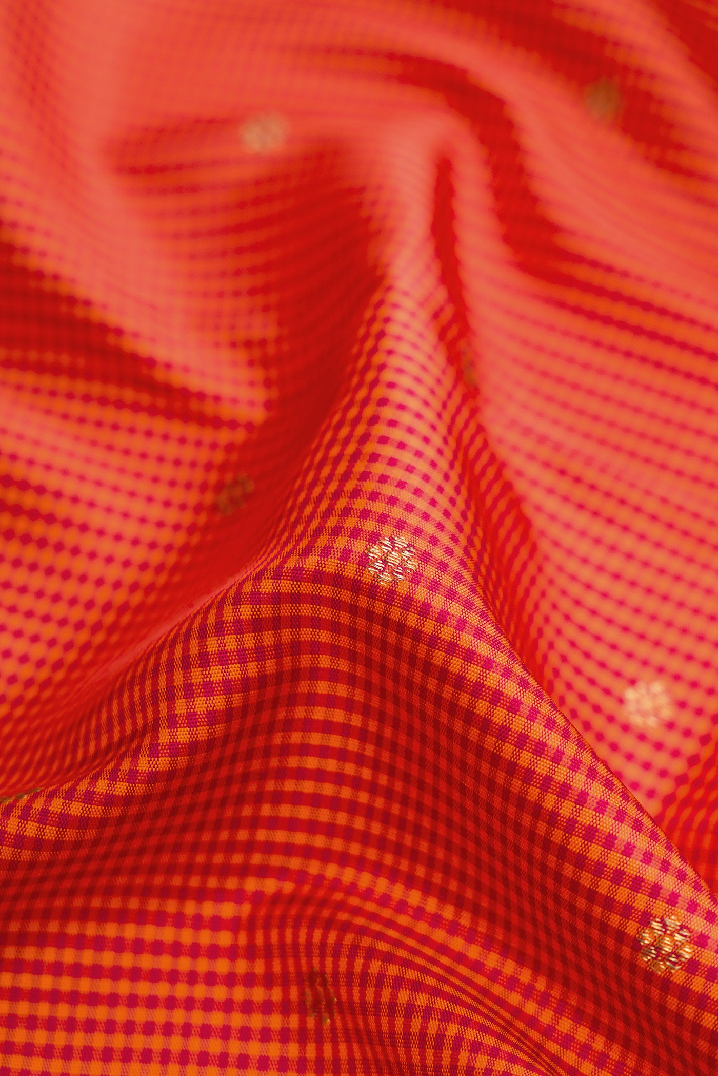 Close up of Pure Silk Pure Zari Orange Dual Tone Kanchipuram Saree with Checked design on the body and Zari Border.  displaying folds