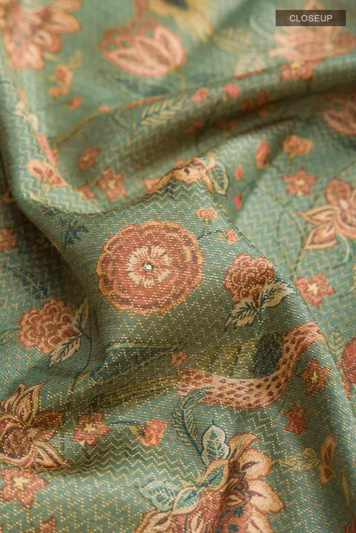 Close up of Green Tussar Silk Saree with Printed design on the body and Zari Border displaying folds