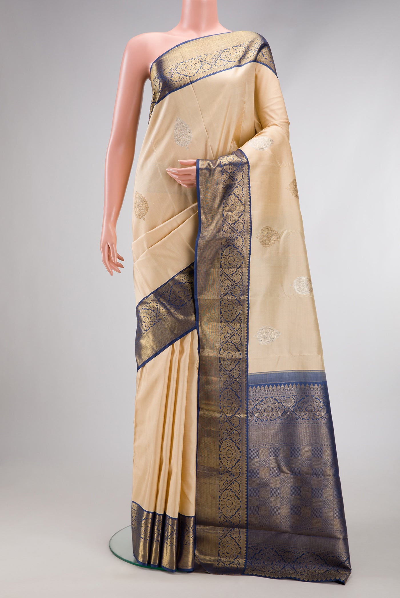 Pure Silk Pure Zari Beige Kanchipuram Saree with Zari Butta on the body and Zari Border.  displayed on a mannequin