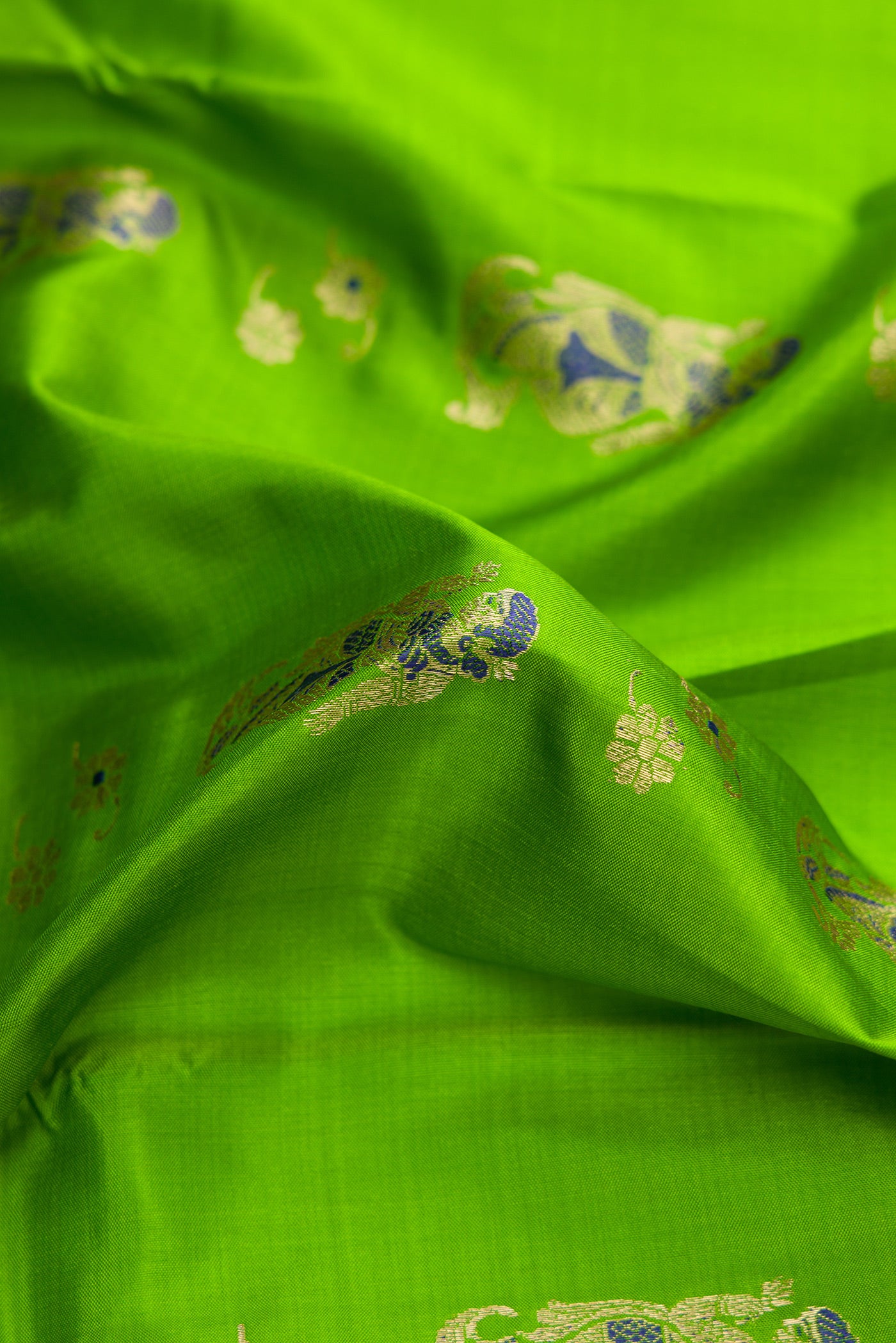 Close up of Parrot Green Dual Tone Baluchari Silk Saree with Zari And Thread Butta on the body and Zari Border.  displaying folds