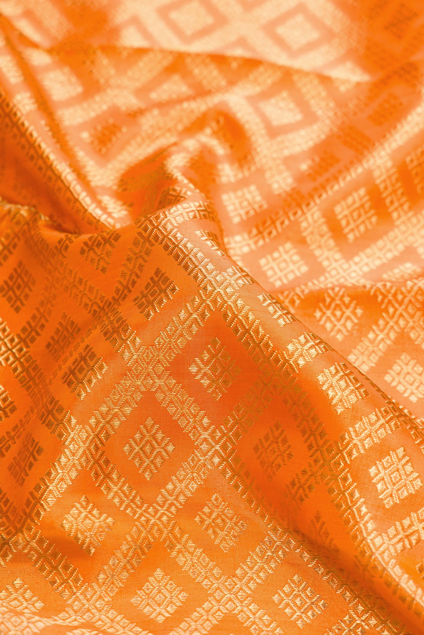 Close up of Pure Silk Pure Zari Orange Dual Tone Kanjivaram Saree with Zari Brocade on the body and Zari Border.  displaying folds