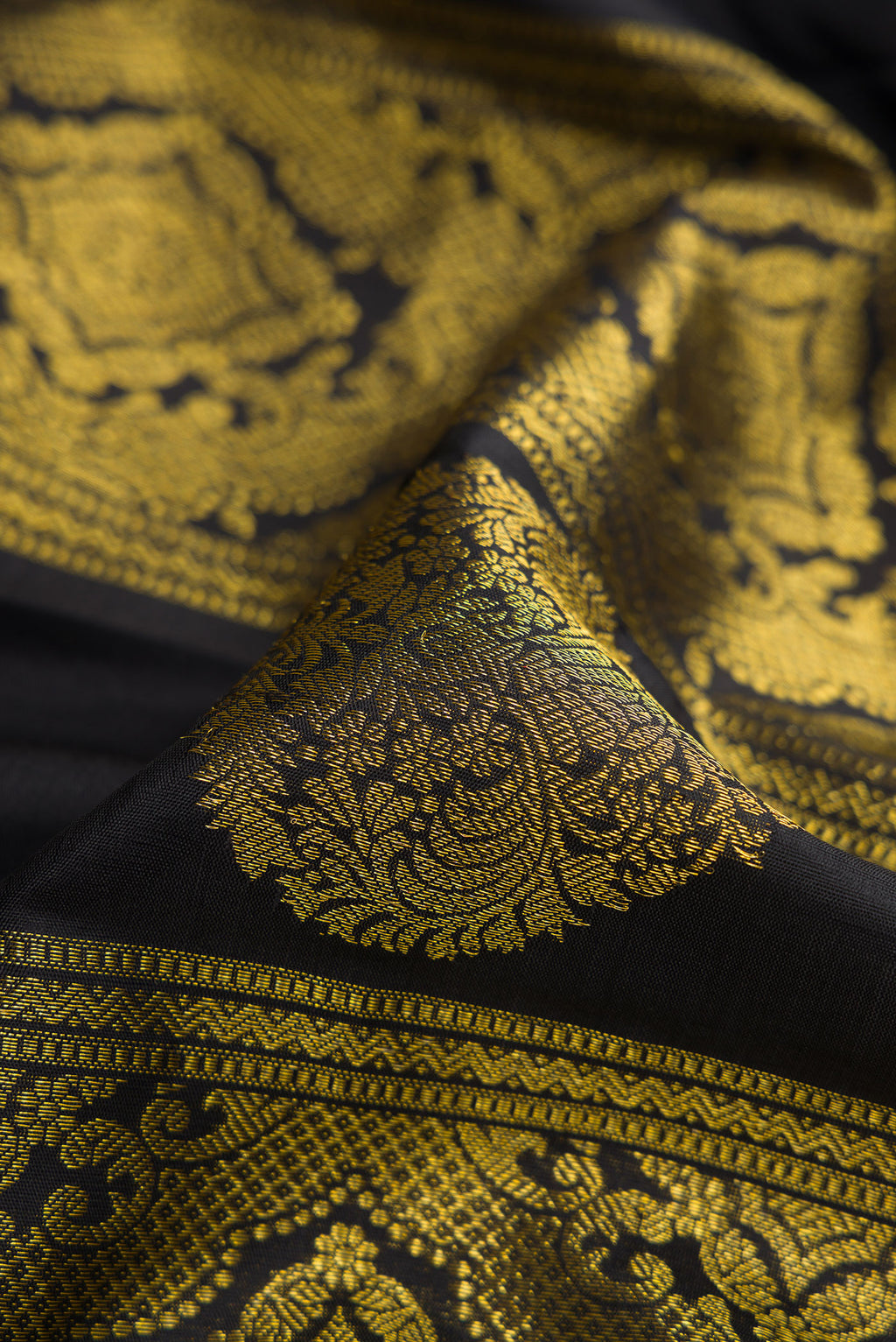 Close up of Black Dual Tone Kanjivaram Silk Saree with Zari Butta on the body and Without Border.  displaying folds