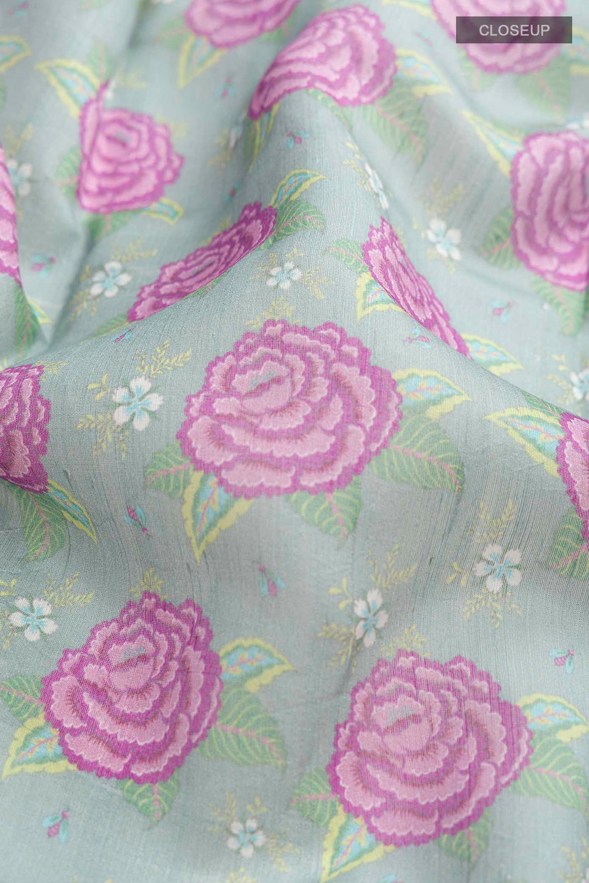 Close up of Green Tussar Silk Saree with Printed design on the body and Zari Border displaying folds