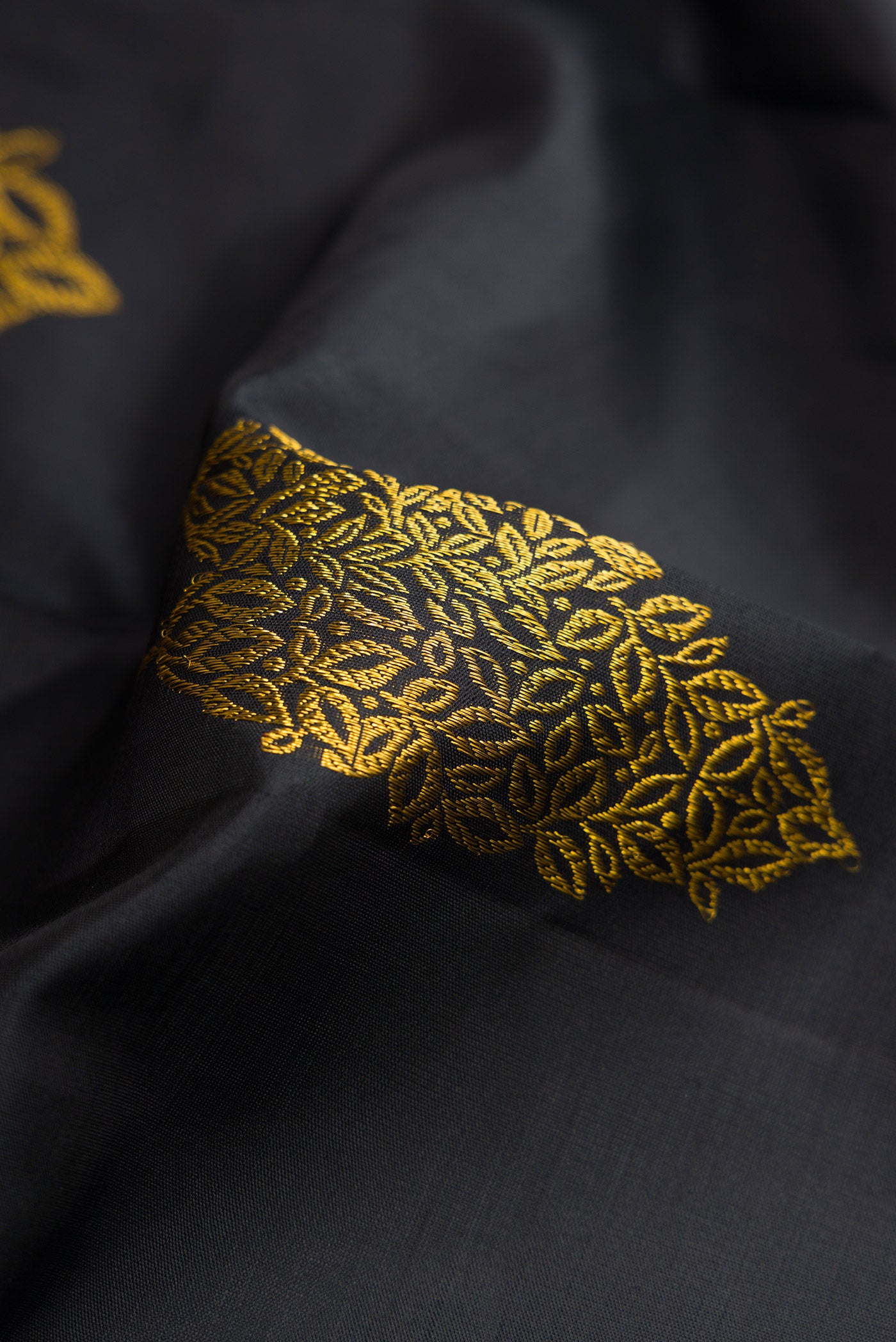 Close up of Black Dual Tone Kanjivaram Silk Saree with Zari Butta on the body and Fancy Border.  displaying folds