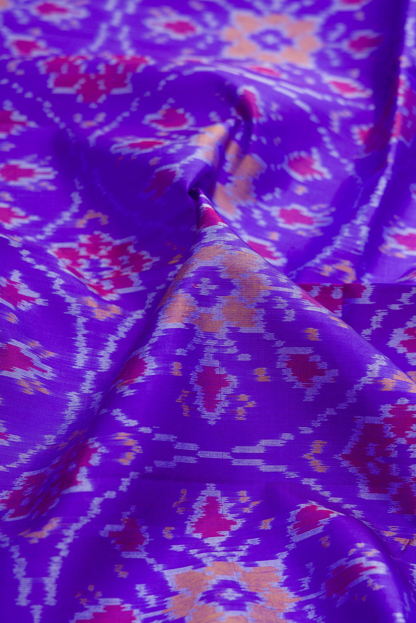 Close up of Orange Dual Tone Double Ikat Saree with Ikat Print on the body and Ikat Border.  displaying folds