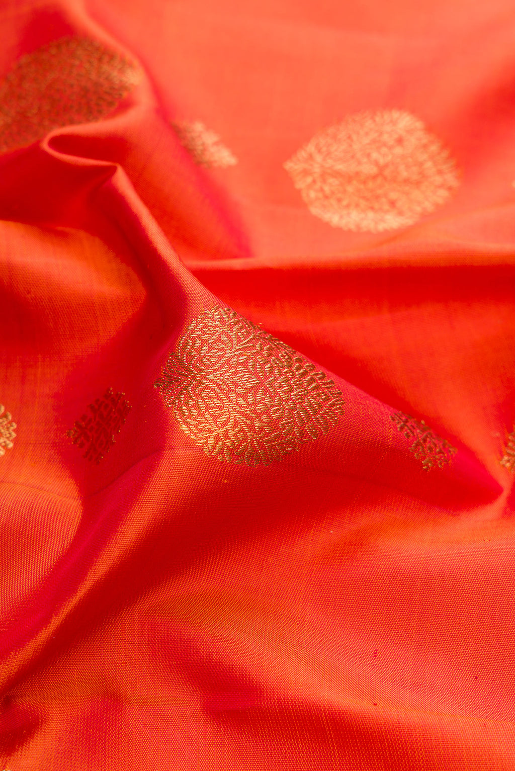 Close up of Pure Silk Pure Zari Orange Kanjivaram Saree with Zari Butta on the body and Fancy Border.  displaying folds