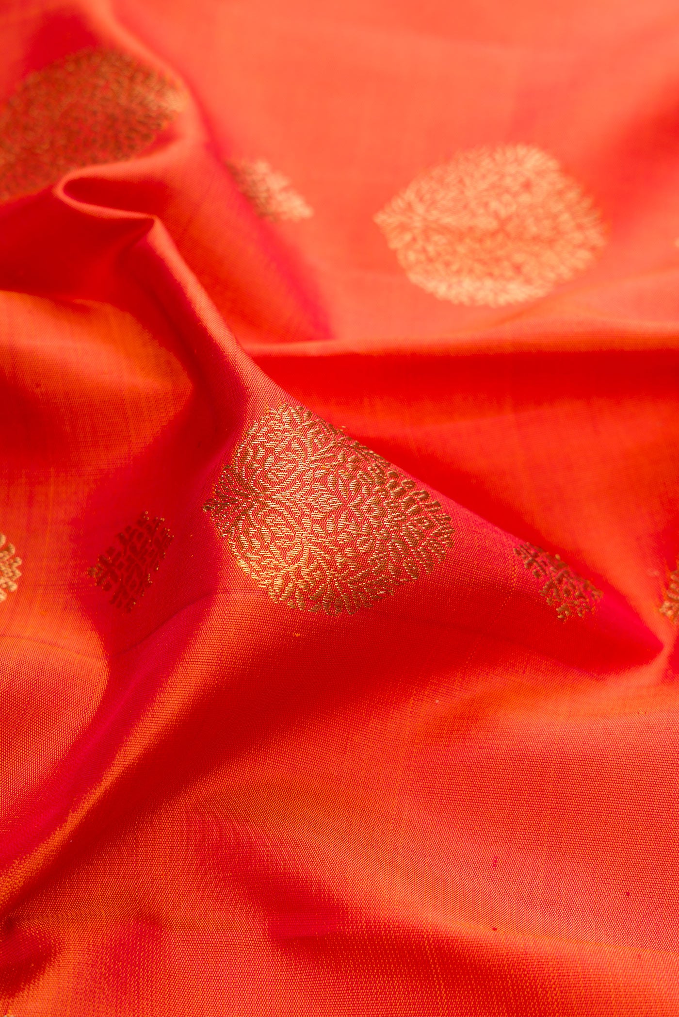 Close up of Pure Silk Pure Zari Orange Kanjivaram Saree with Zari Butta on the body and Fancy Border.  displaying folds