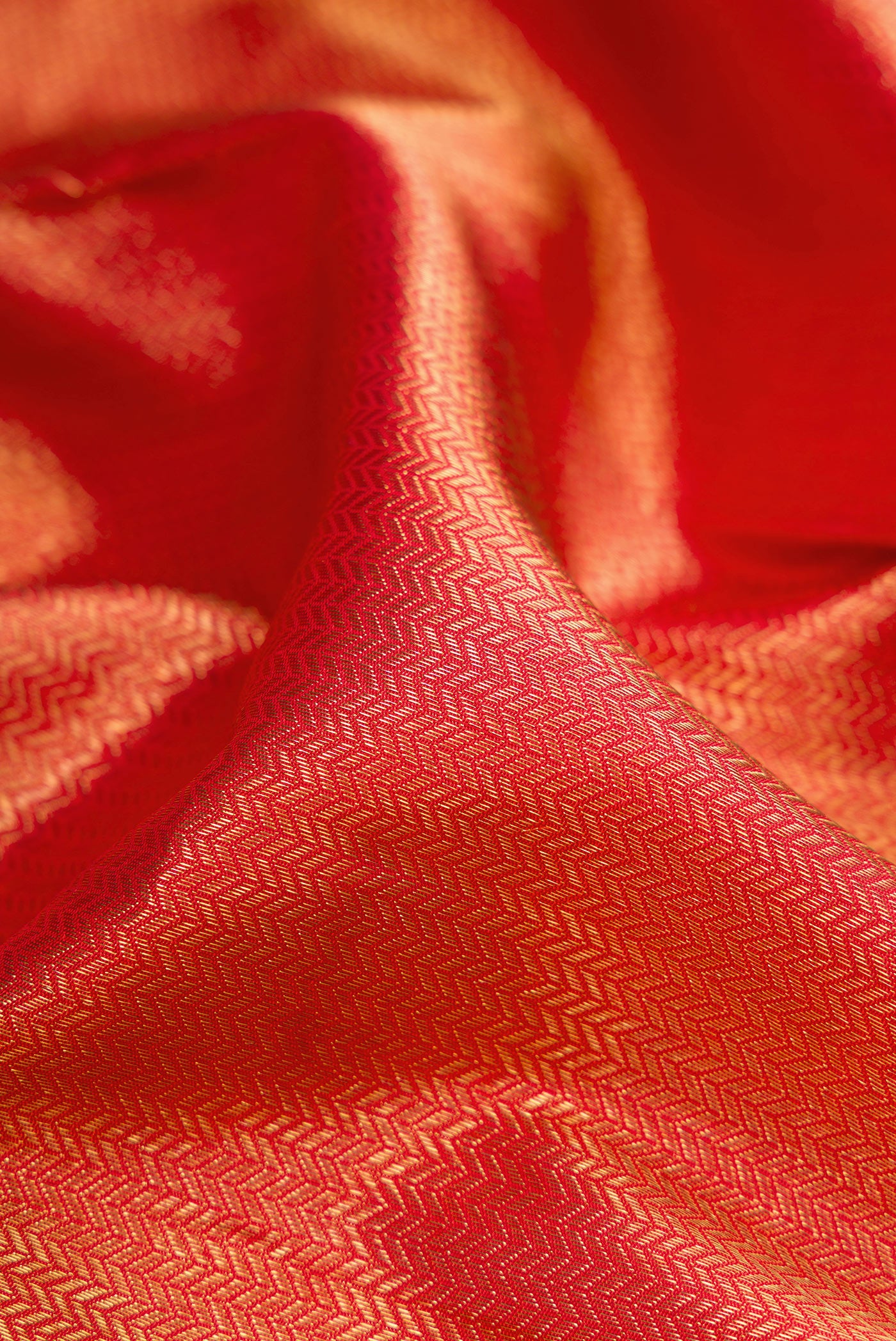 Close up of Pure Silk Pure Zari Red Dual Tone Kanjivaram Saree with Zari Brocade on the body and Zari Border.  displaying folds