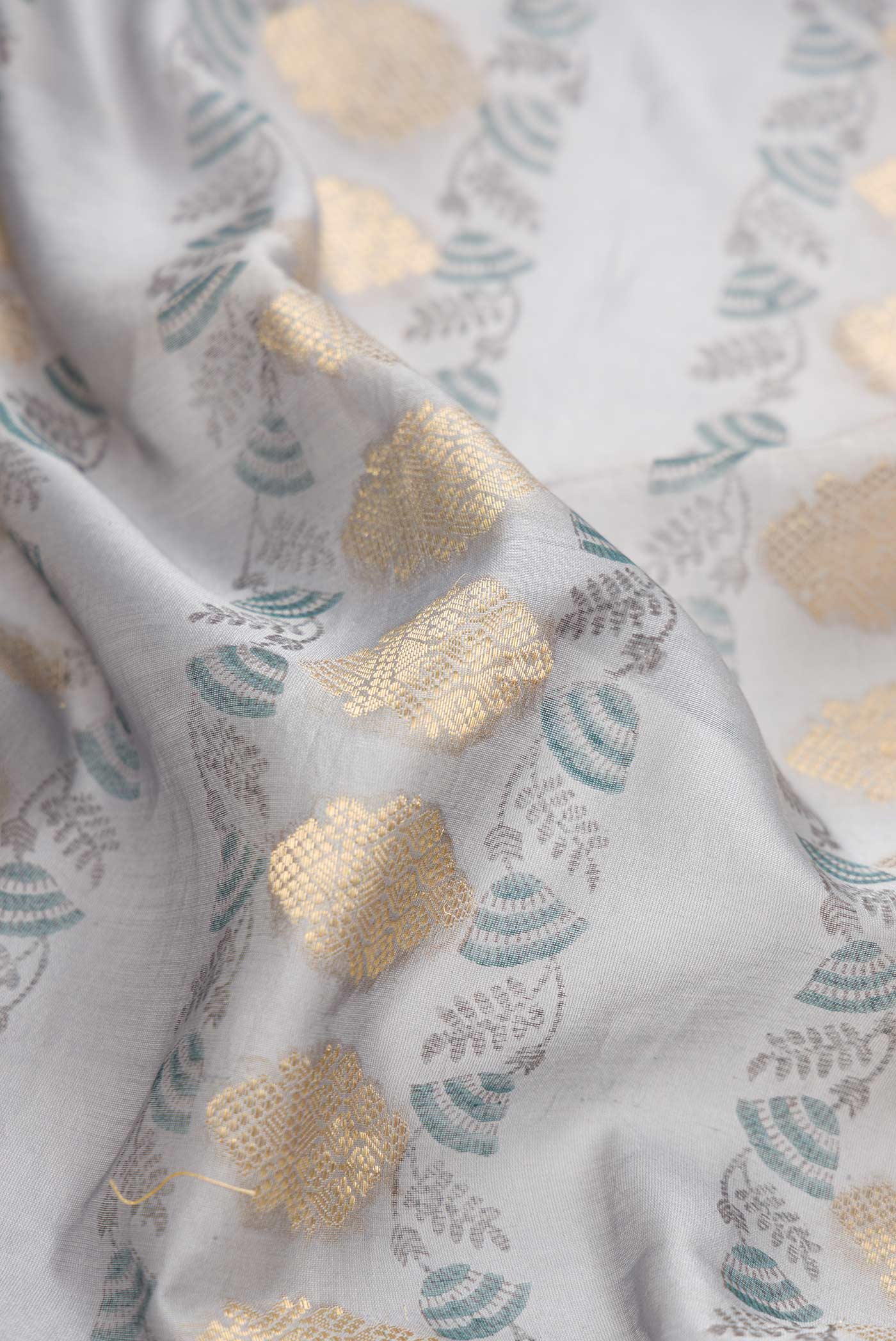 Close up of Grey Dual Tone Tussar Silk Saree with Zari Butta on the body and Embroidery Border.  displaying folds