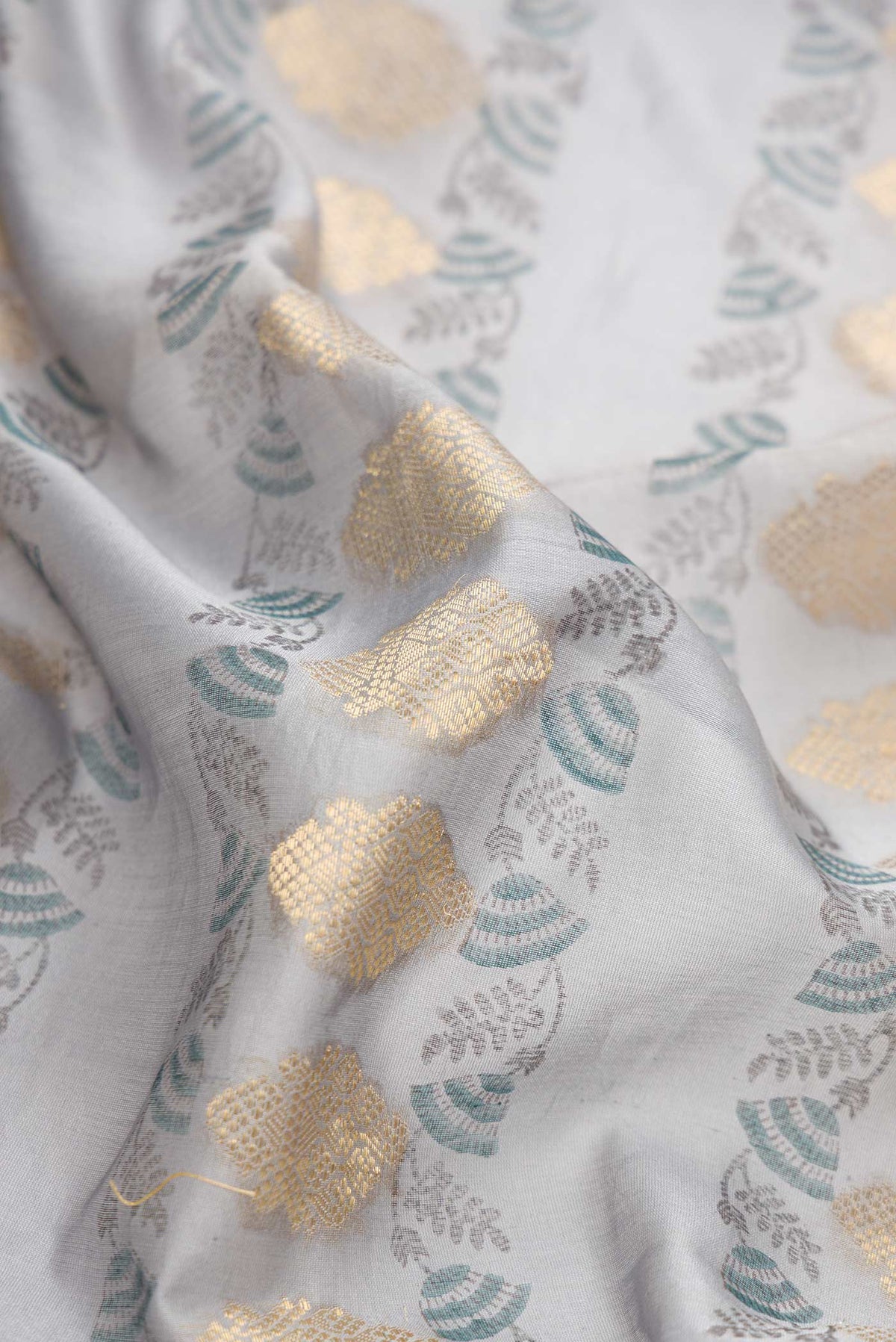Close up of Grey Dual Tone Tussar Silk Saree with Zari Butta on the body and Embroidery Border.  displaying folds