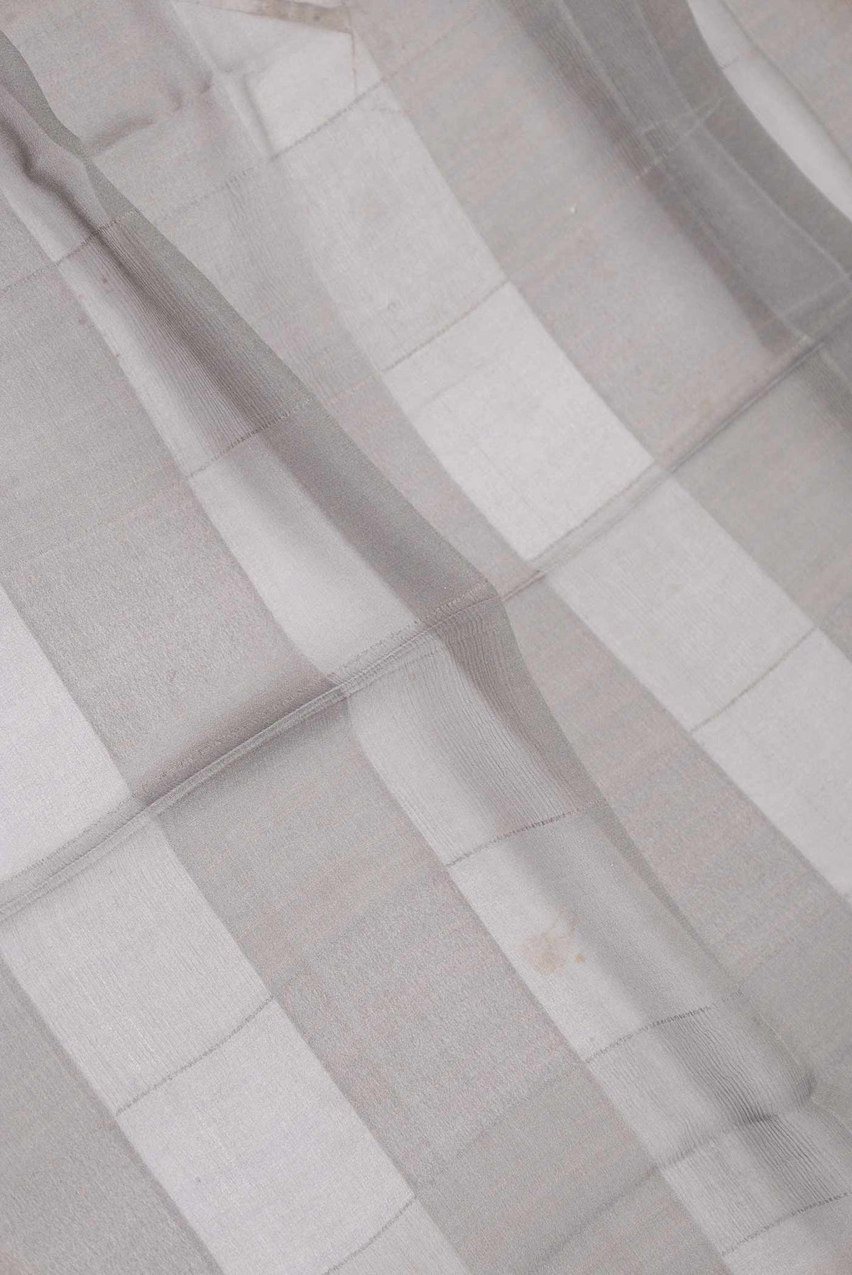 Close up of Grey Dual Tone Mysore Georgette Saree With Printed design on the body and Zari Border displaying folds