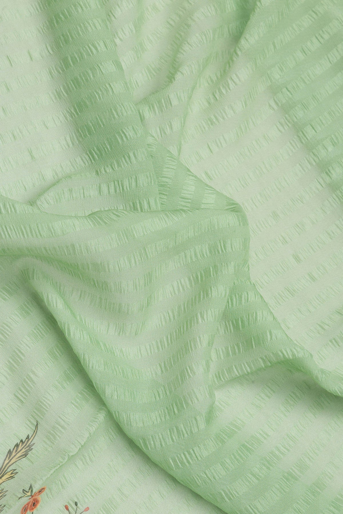 Close up of Pista Green Dual Tone Mysore Chiffon Saree with Printed design on the body and Zari Border.  displaying folds