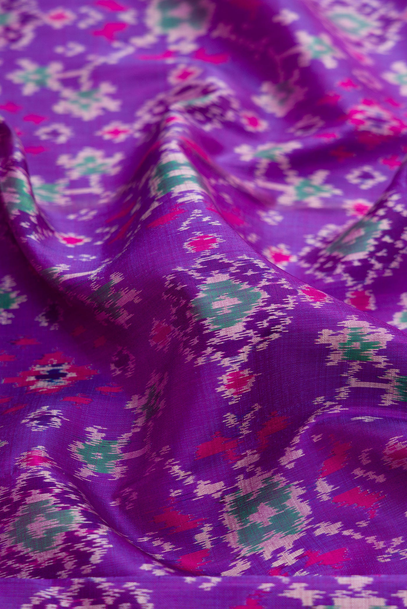 Close up of Purple Dual Tone Kanjivaram Silk Saree with Ikat Print on the body and Zari Border.  displaying folds