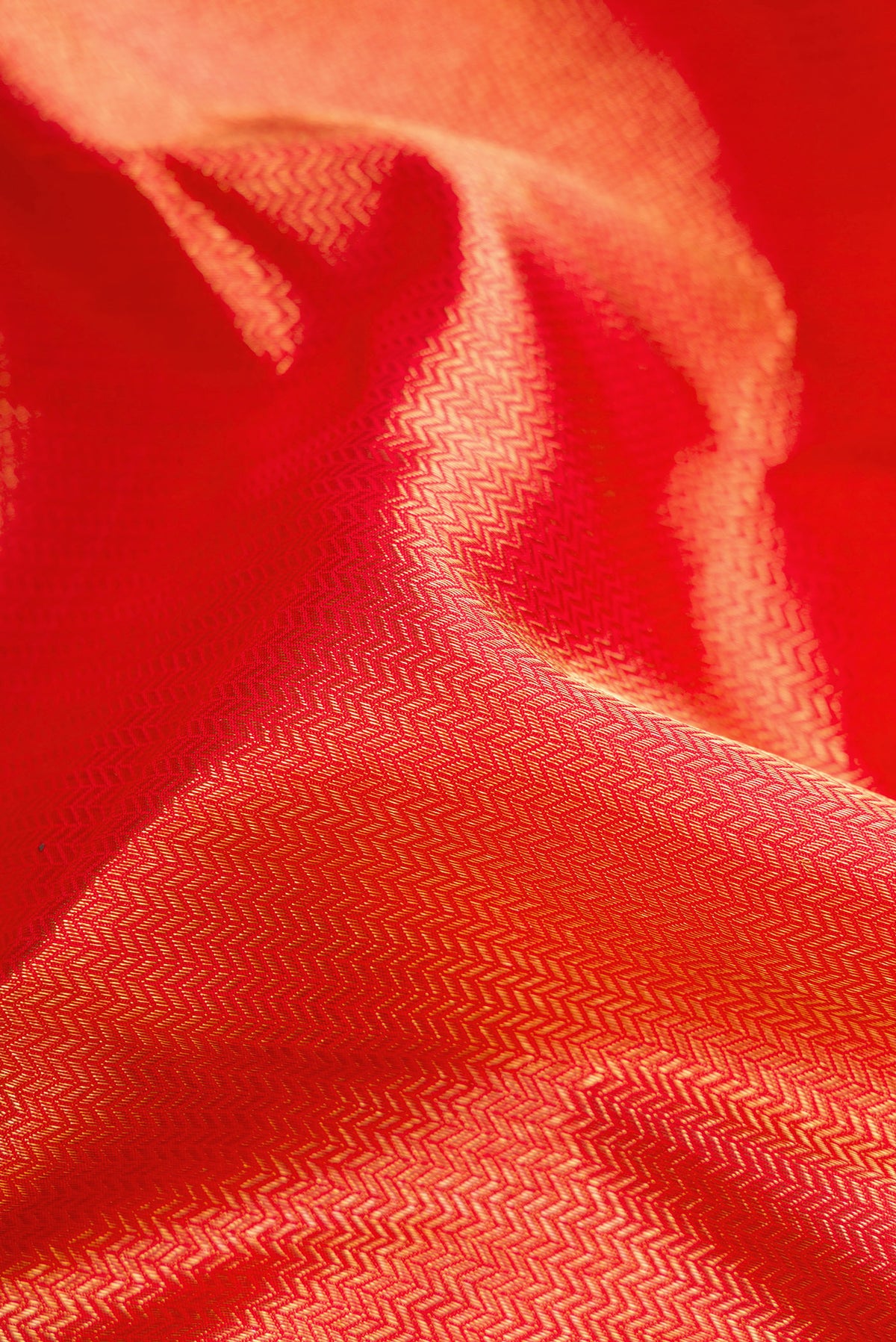 Close up of Pure Silk Pure Zari Red Dual Tone Kanjivaram Saree with Zari Brocade on the body and Zari Border.  displaying folds