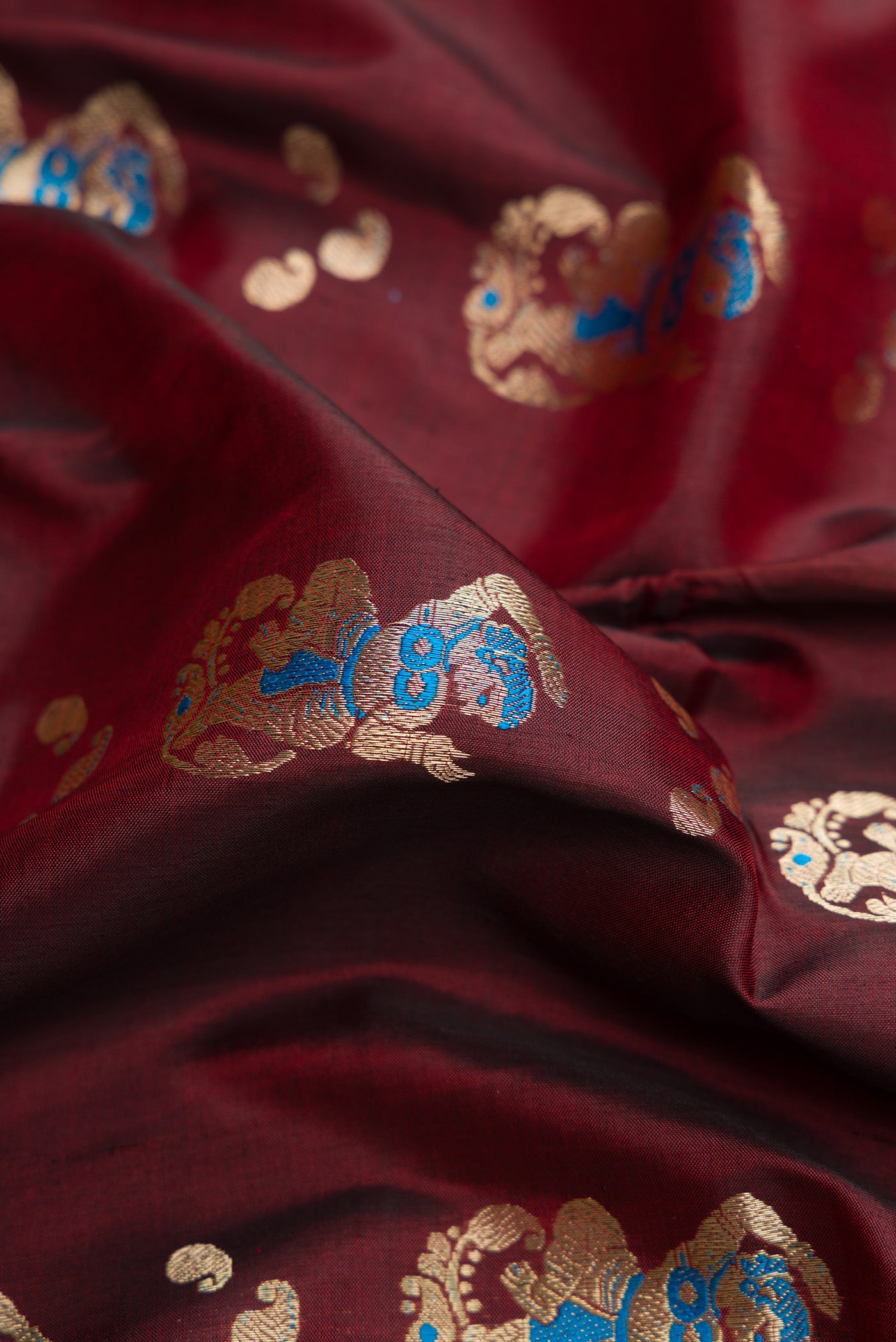Close up of Maroon Dual Tone Baluchari Silk Saree with Thread Butta on the body and Thread Border.  displaying folds
