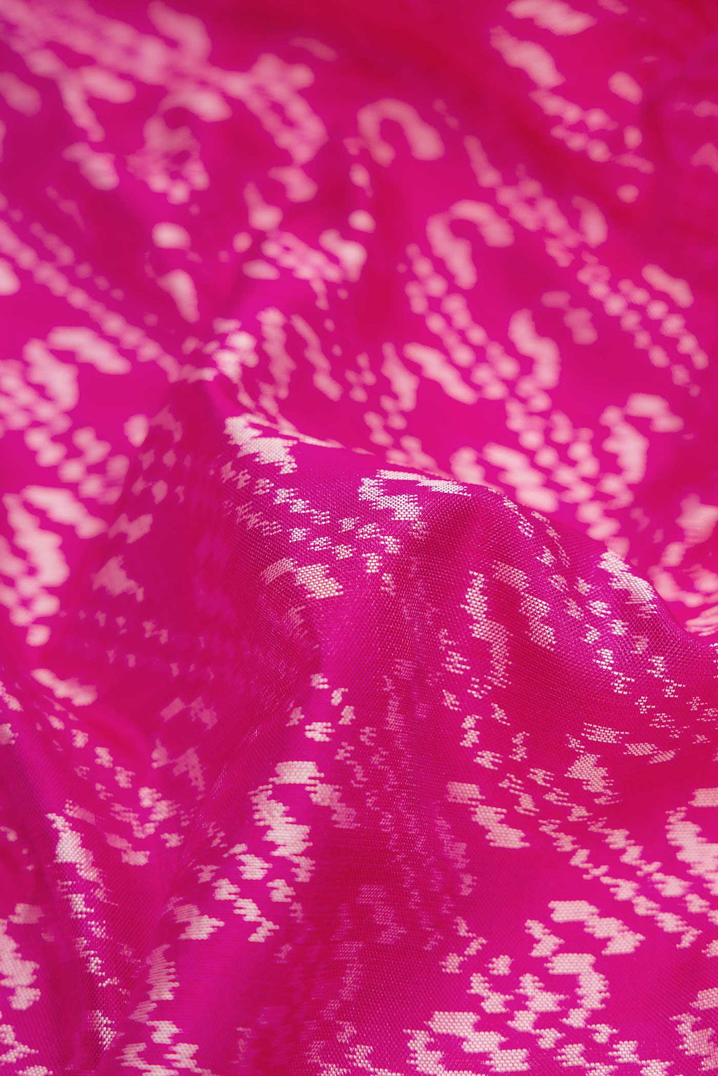 Close up of Pink Dual Tone Rajkot Patola Silk Saree with Ikat Print on the body and Plain Border displaying folds