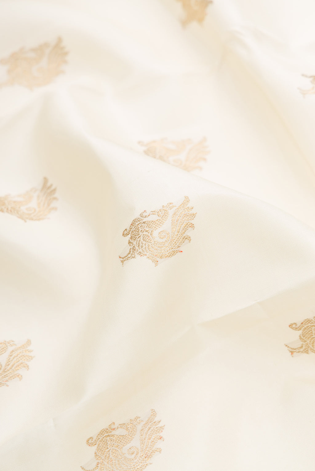 Close up of Pure Silk Pure Zari Off White Dual Tone Kanchipuram Saree with Zari Butta on the body and Zari Border.  displaying folds