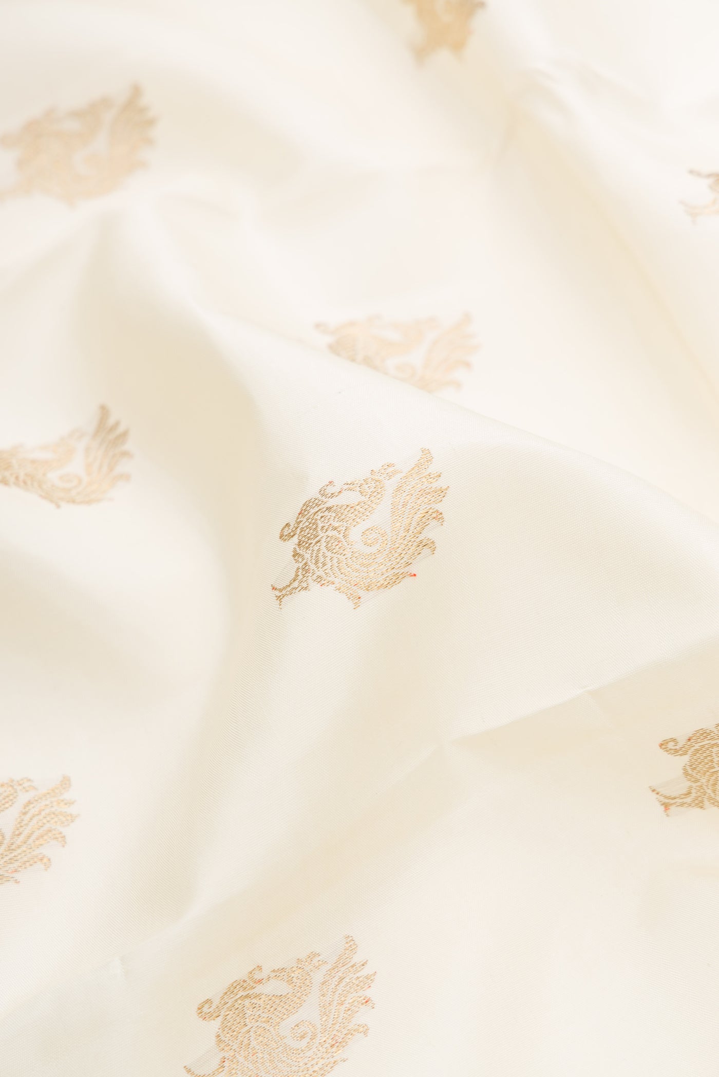 Close up of Pure Silk Pure Zari Off White Dual Tone Kanchipuram Saree with Zari Butta on the body and Zari Border.  displaying folds