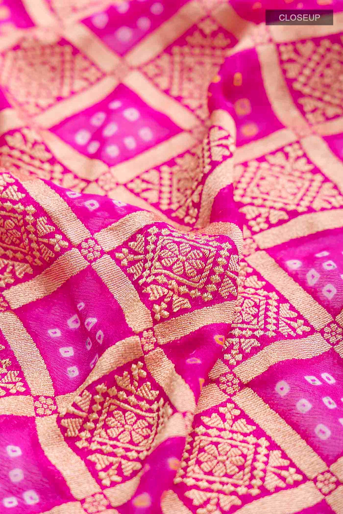 Close up of Pink Banarasi Georgette Saree with Bandhani Print on the body and Zari Border displaying folds