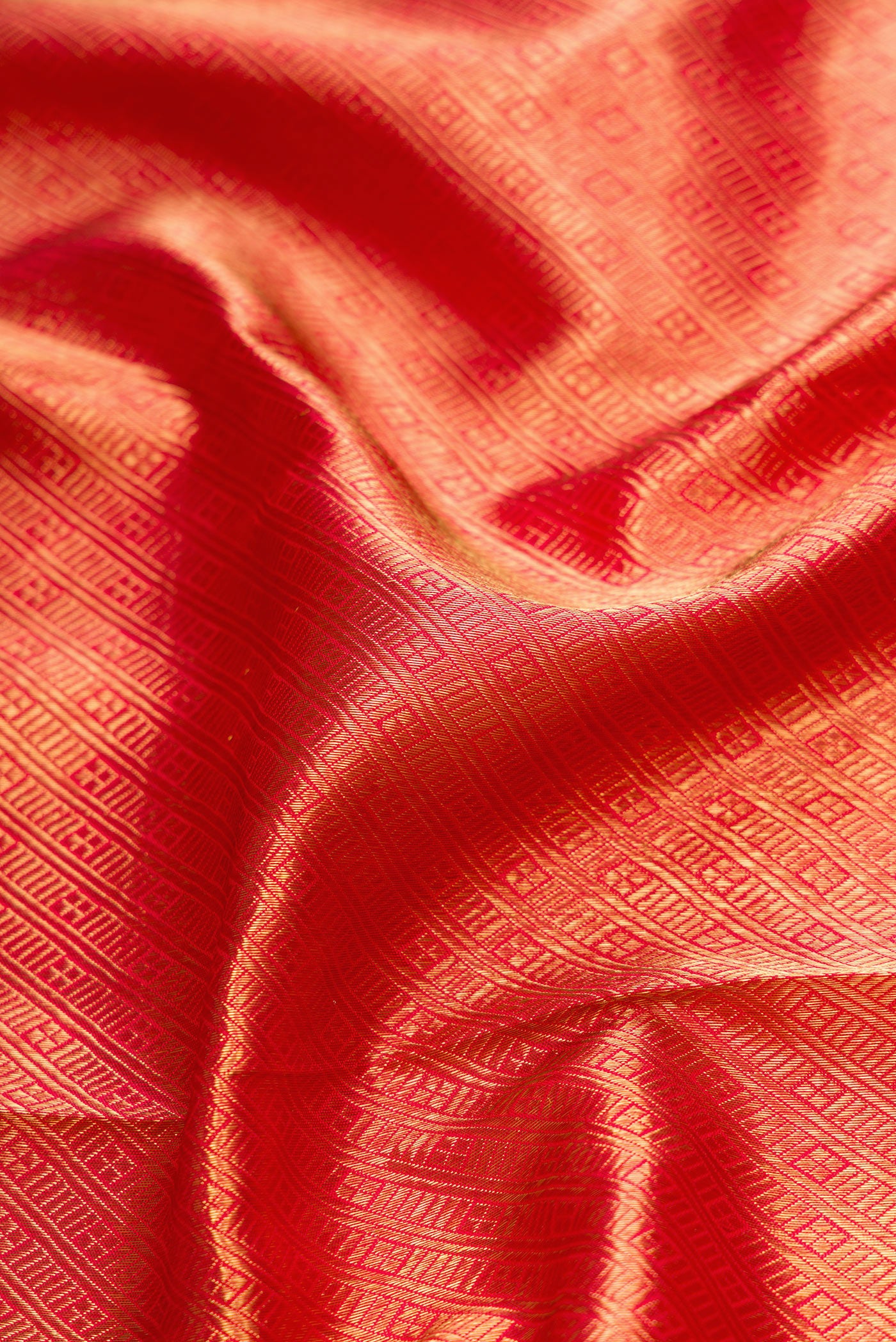 Close up of Pure Silk Pure Zari Red Dual Tone Kanjivaram Saree with Zari Brocade on the body and Zari Border.  displaying folds