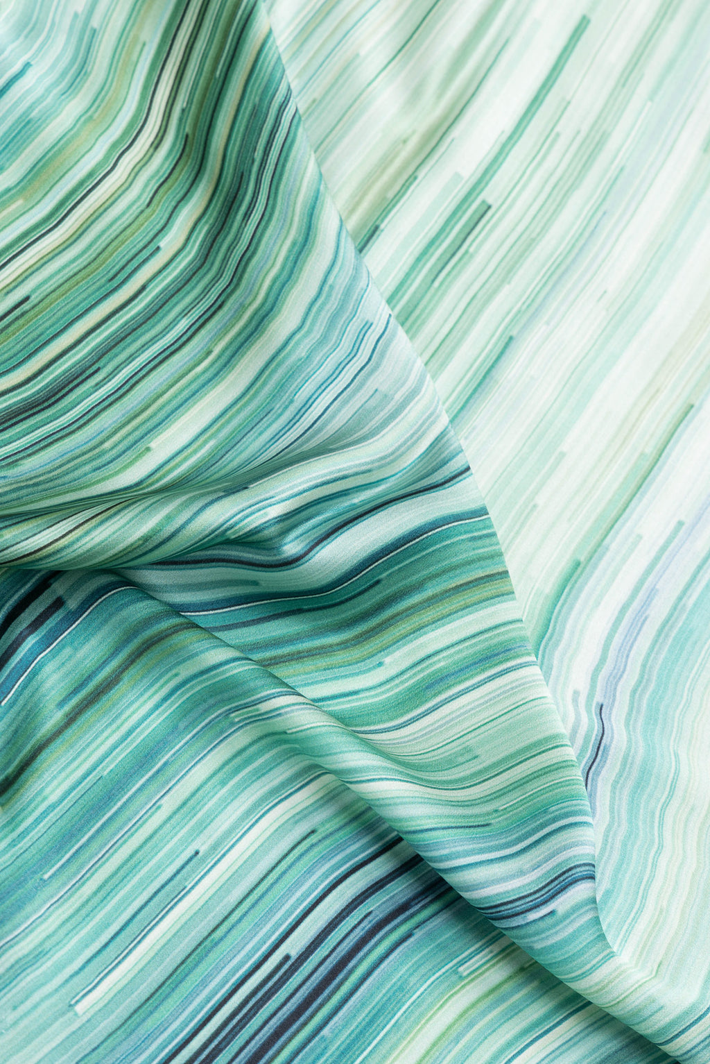 Close up of Light Green Dual Tone Mysore Crepe Saree with Printed design on the body and Printed Border.  displaying folds