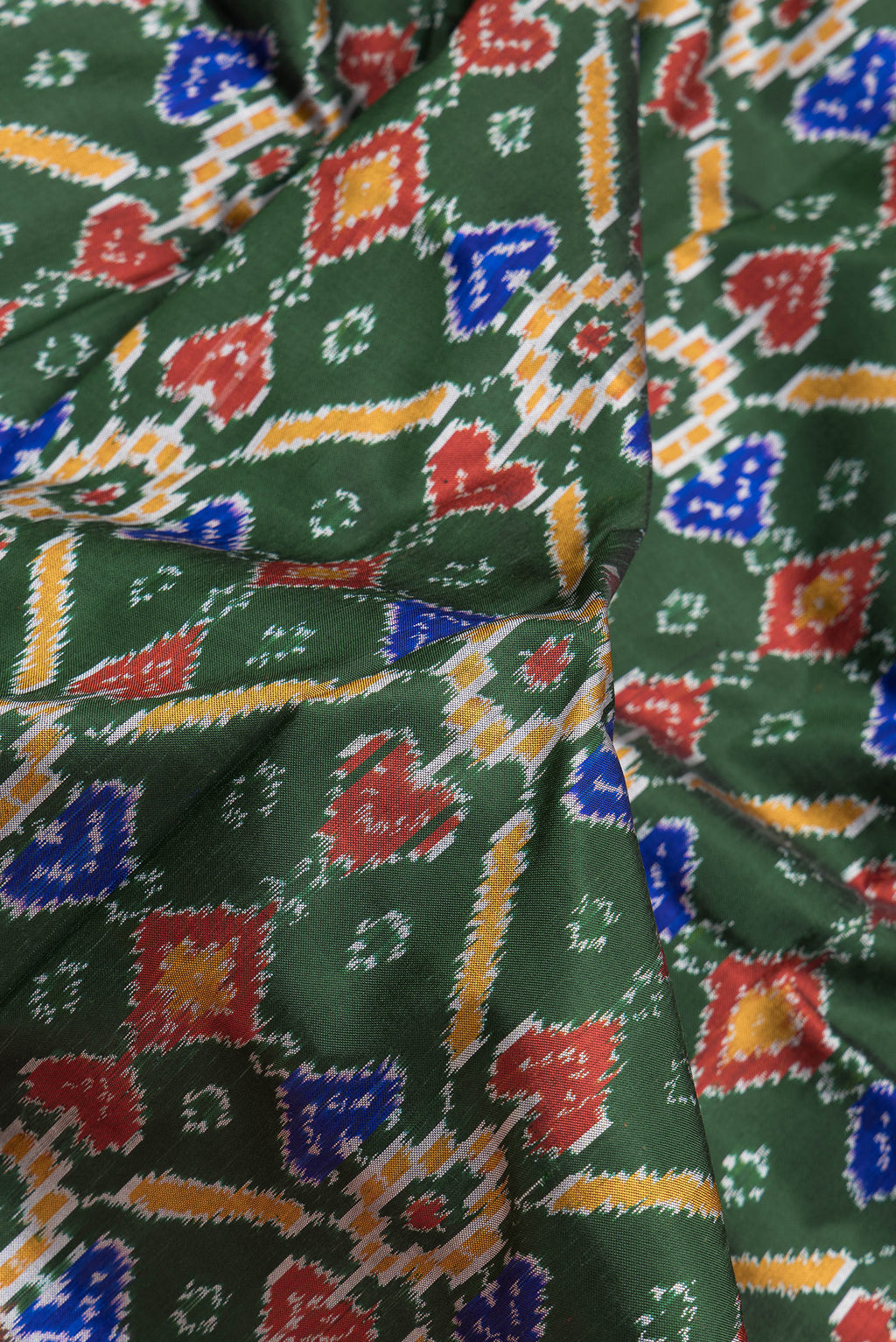 Close up of Bottle Green Dual Tone Kanchipuram Silk Saree with Ikat Print on the body and Zari Border.  displaying folds