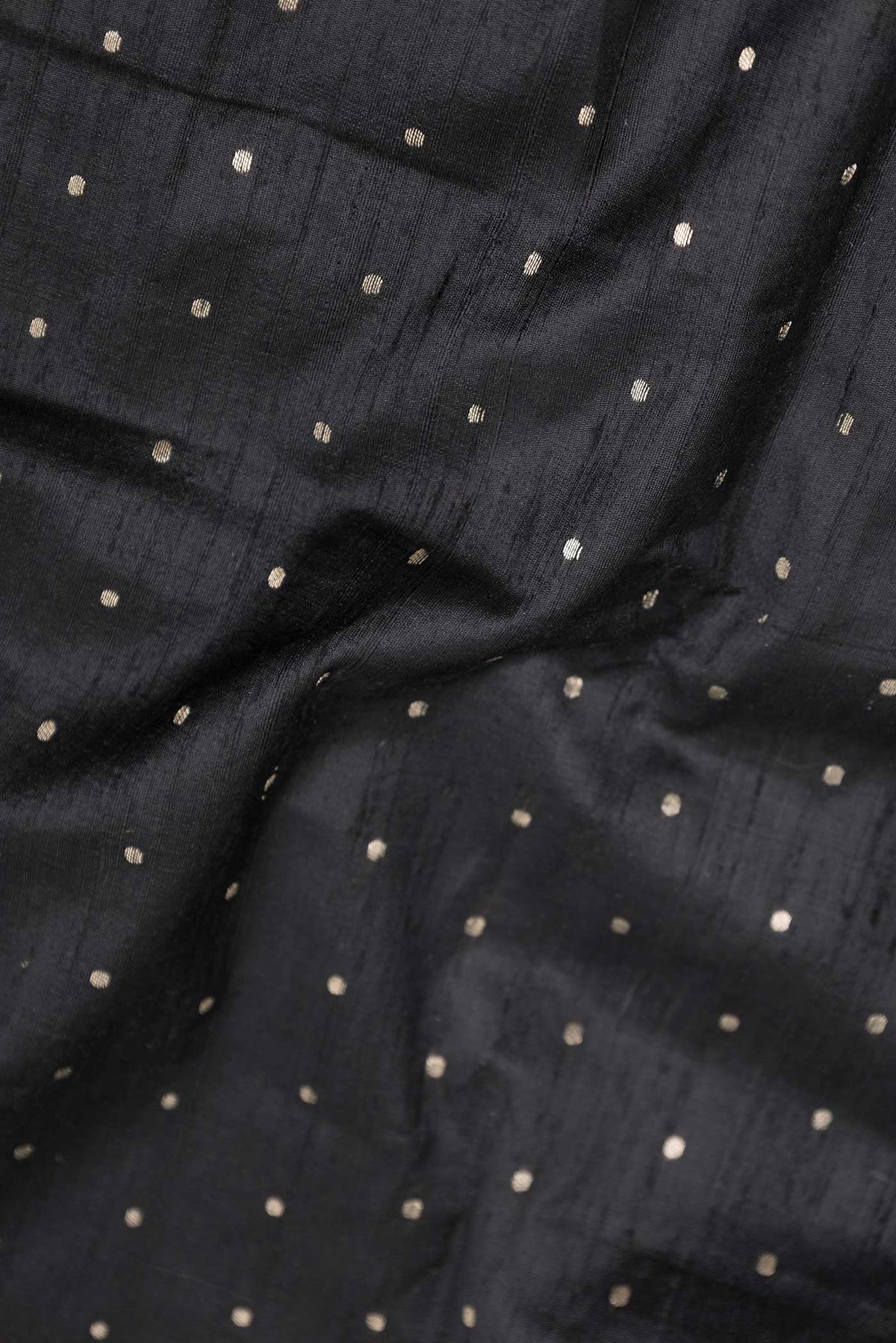 Close up of Black Dual Tone Raw Silk Saree with Zari Butta on the body and Zari Border displaying folds