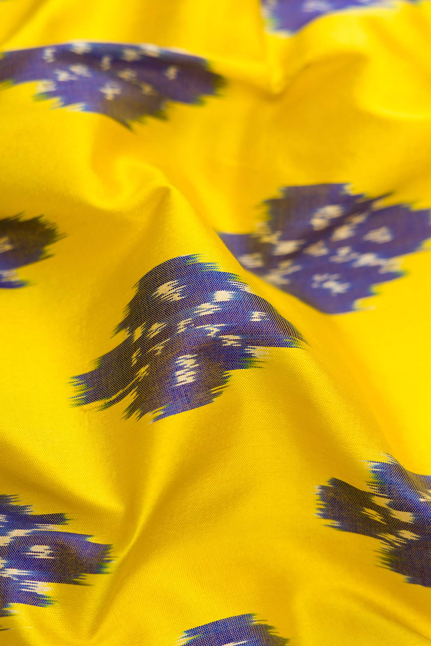 Close up of Lemon Yellow Dual Tone Double Ikat Saree with Ikat Print on the body and Ikat Border.  displaying folds