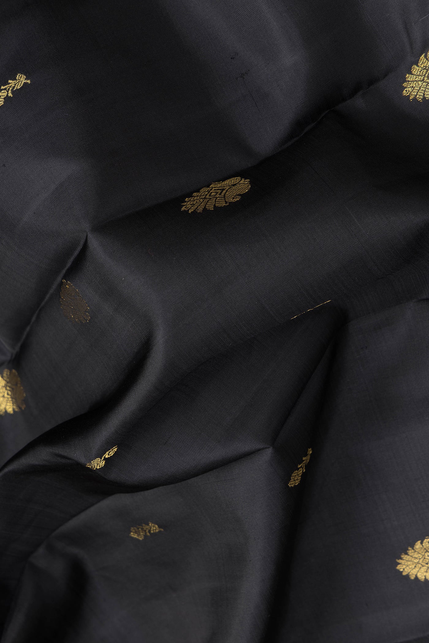 Close up of Black Dual Tone Kanjivaram Silk Saree with Zari Butta on the body and Zari Border.  displaying folds