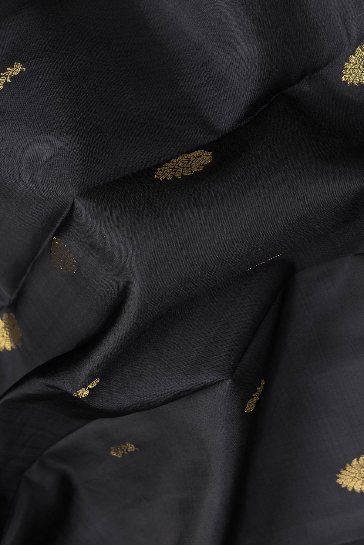 Close up of Black Dual Tone Kanjivaram Silk Saree with Zari Butta on the body and Zari Border.  displaying folds