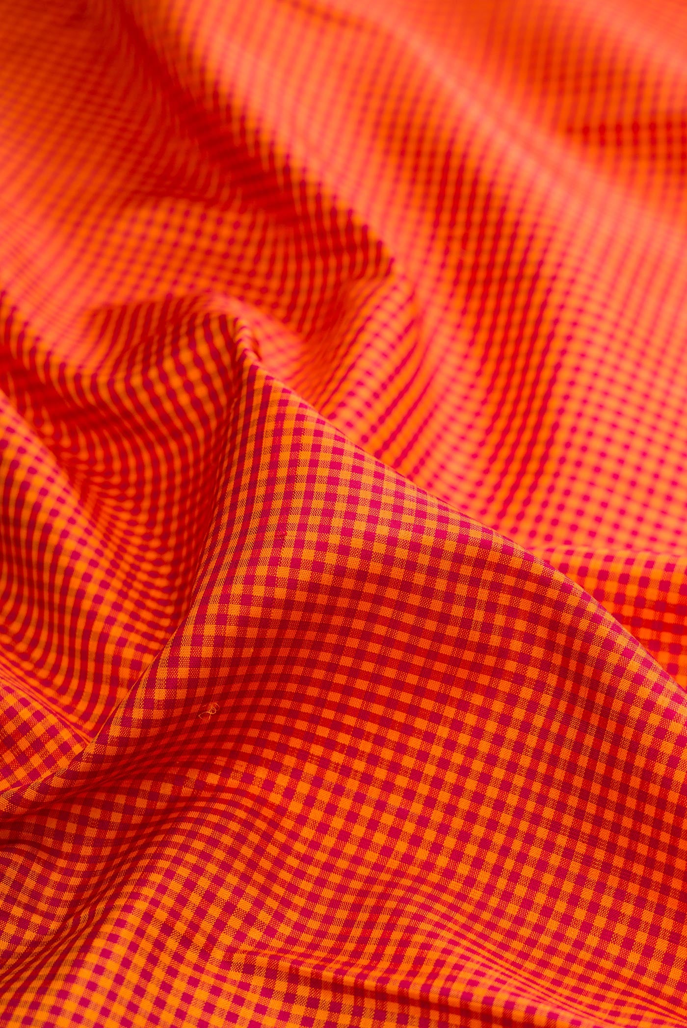 Close up of Pure Silk Pure Zari Orange Kanchipuram Saree with Checked design on the body and Temple Border.  displaying folds