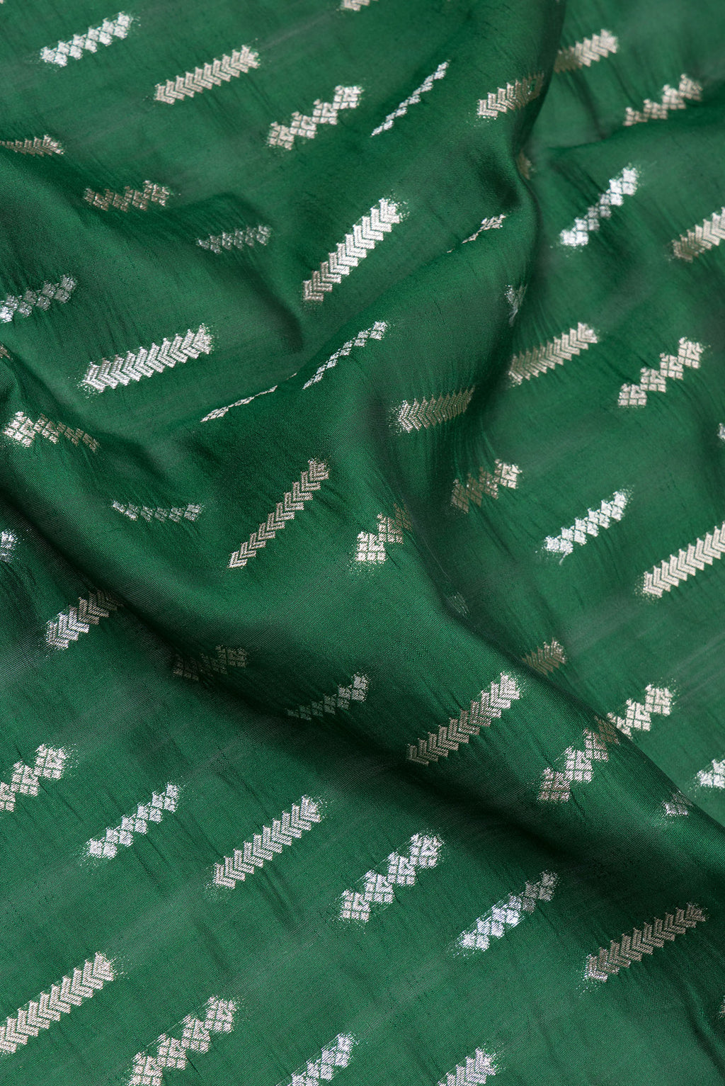 Close up of Bottle Green Tussar Silk Saree with Zari Butta on the body and Zari Border.  displaying folds