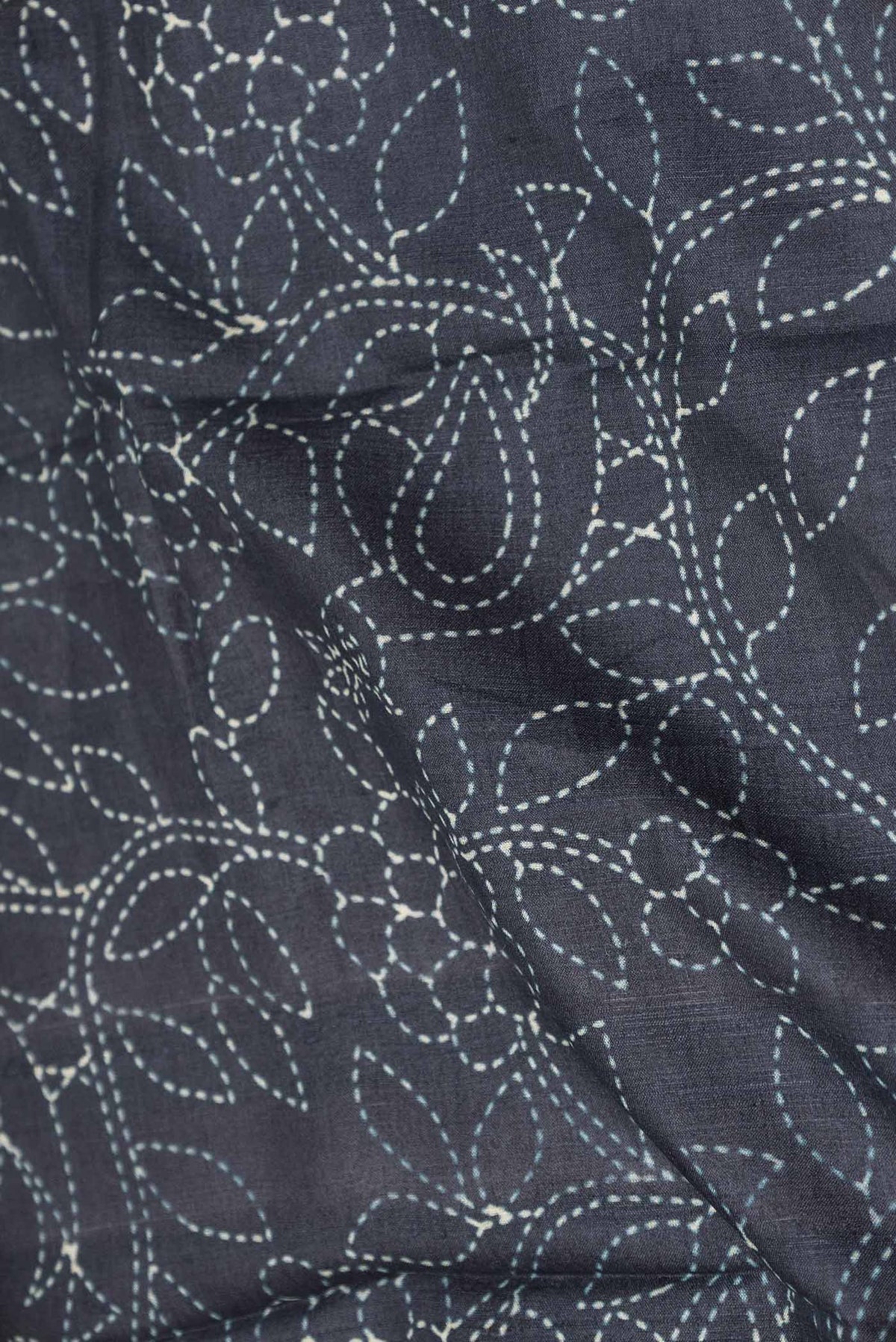 Close up of Black Dual Tone Tussar Silk Saree with Printed design on the body and Zari Border displaying folds