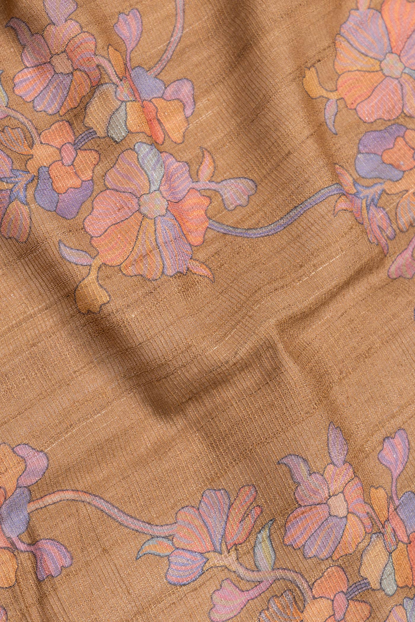 Close up of Brown Dual Tone Tussar Silk Saree with Printed design on the body and Zari Border.  displaying folds