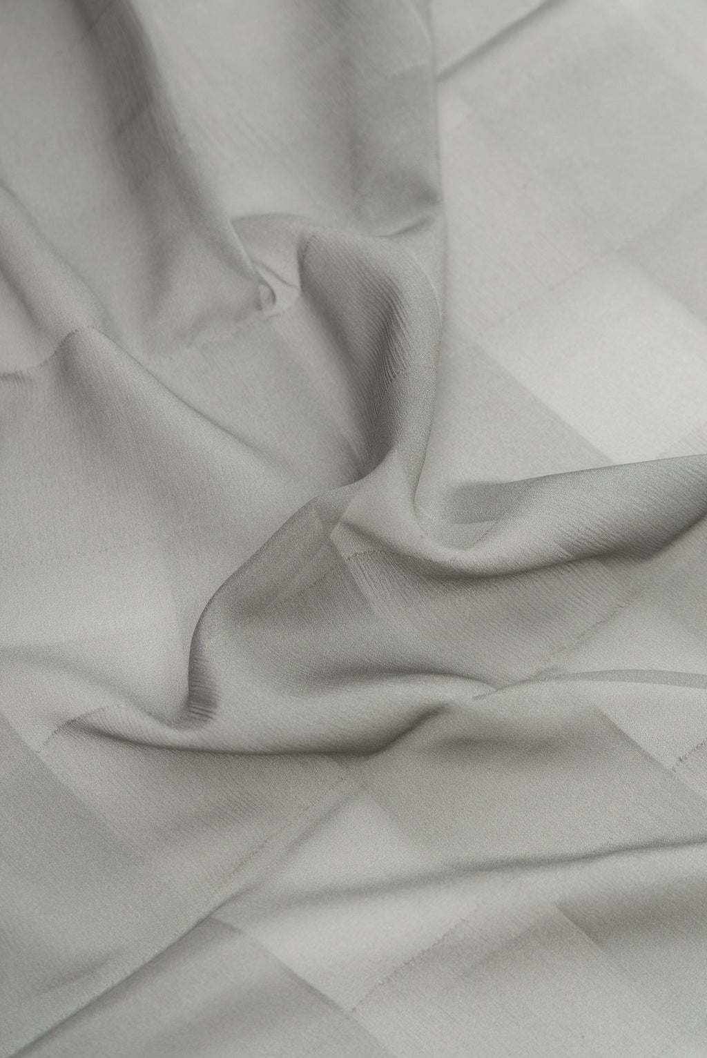Close up of Grey Dual Tone Mysore Crepe Saree with Printed design on the body and Fancy Border.  displaying folds